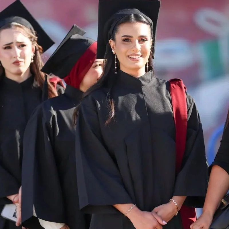 Group of graduating students in caps and gowns standing outdoors, smiling.