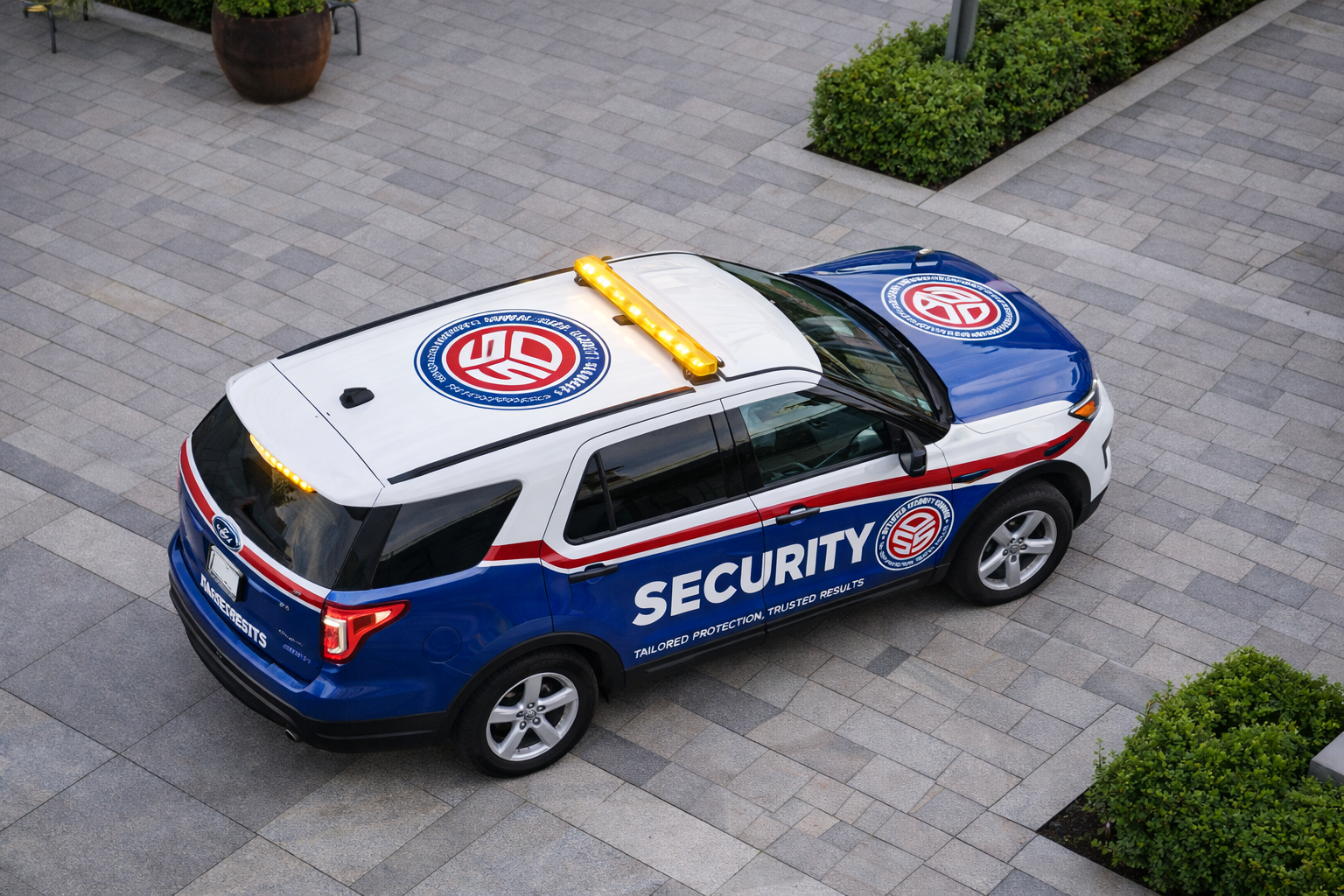 A security vehicle parked on a paved surface, with the word 'SECURITY' and the logo of the security company on its side and roof, and a yellow warning light on top.