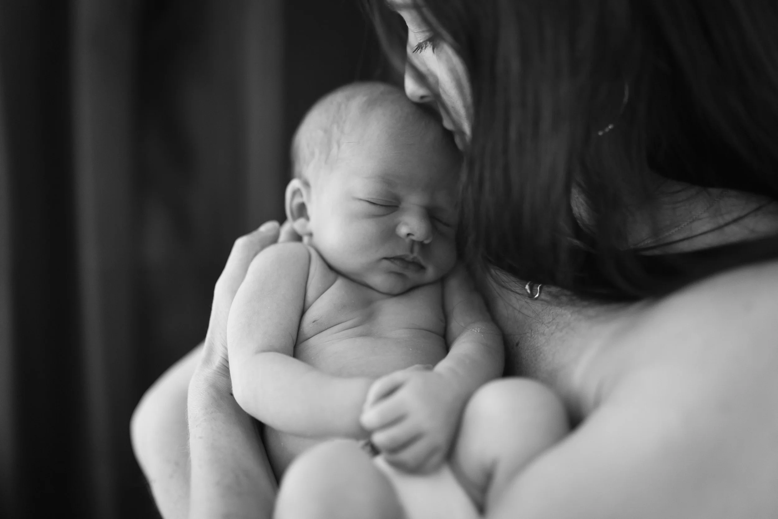Black and white photo of a woman holding a sleeping newborn baby.