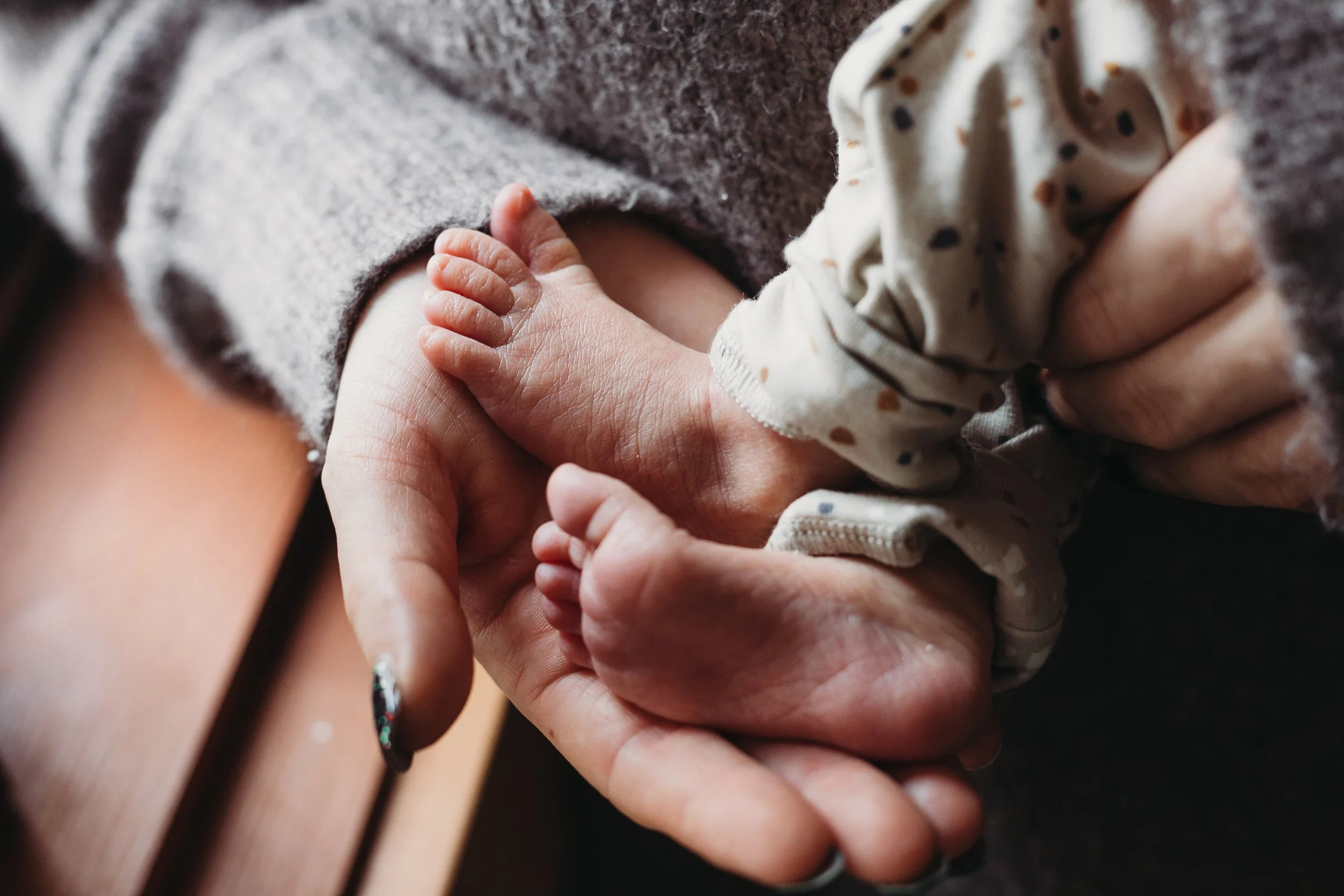 Close-up of baby's feet held gently by adult hands