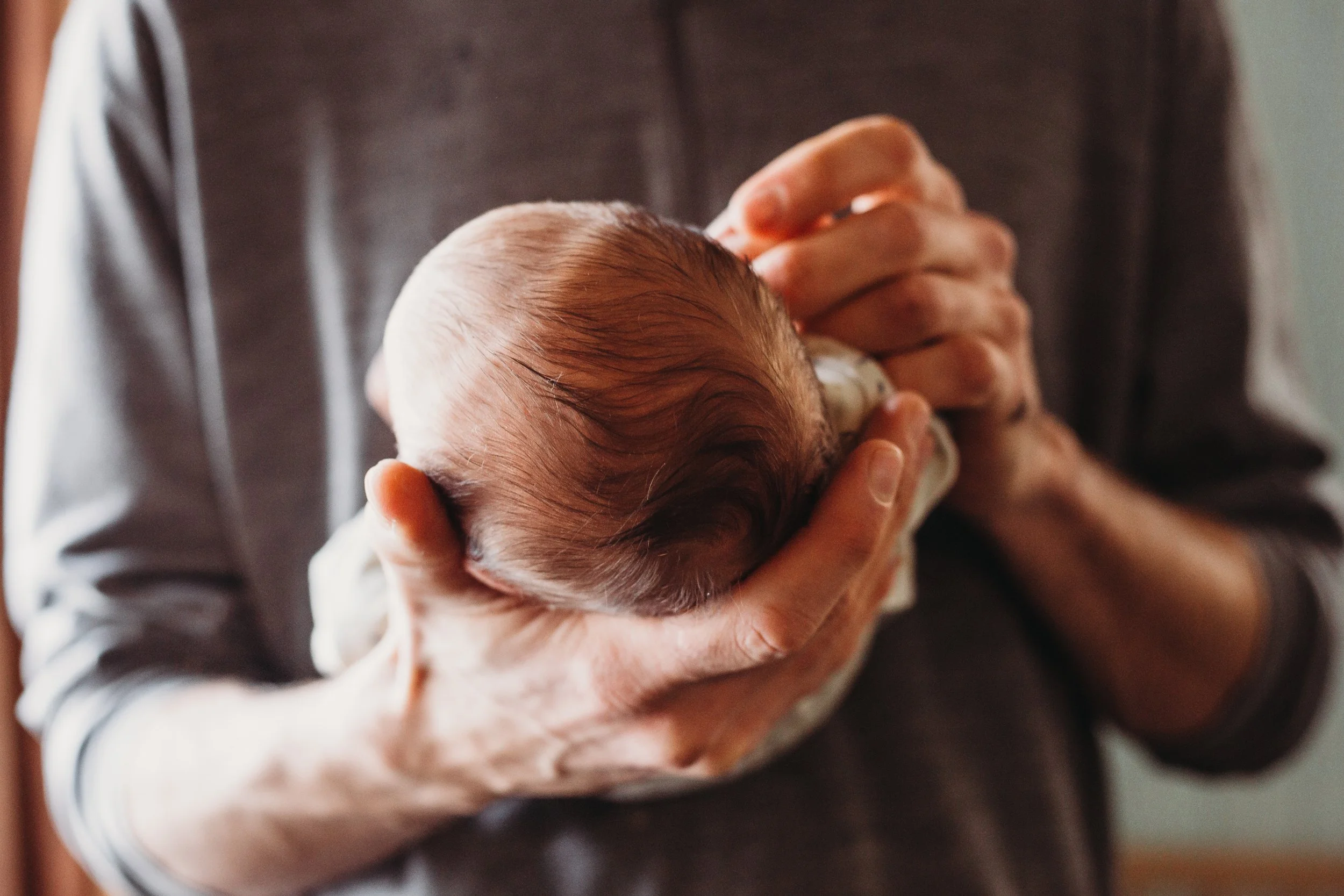 Close-up of a person gently holding a newborn baby.