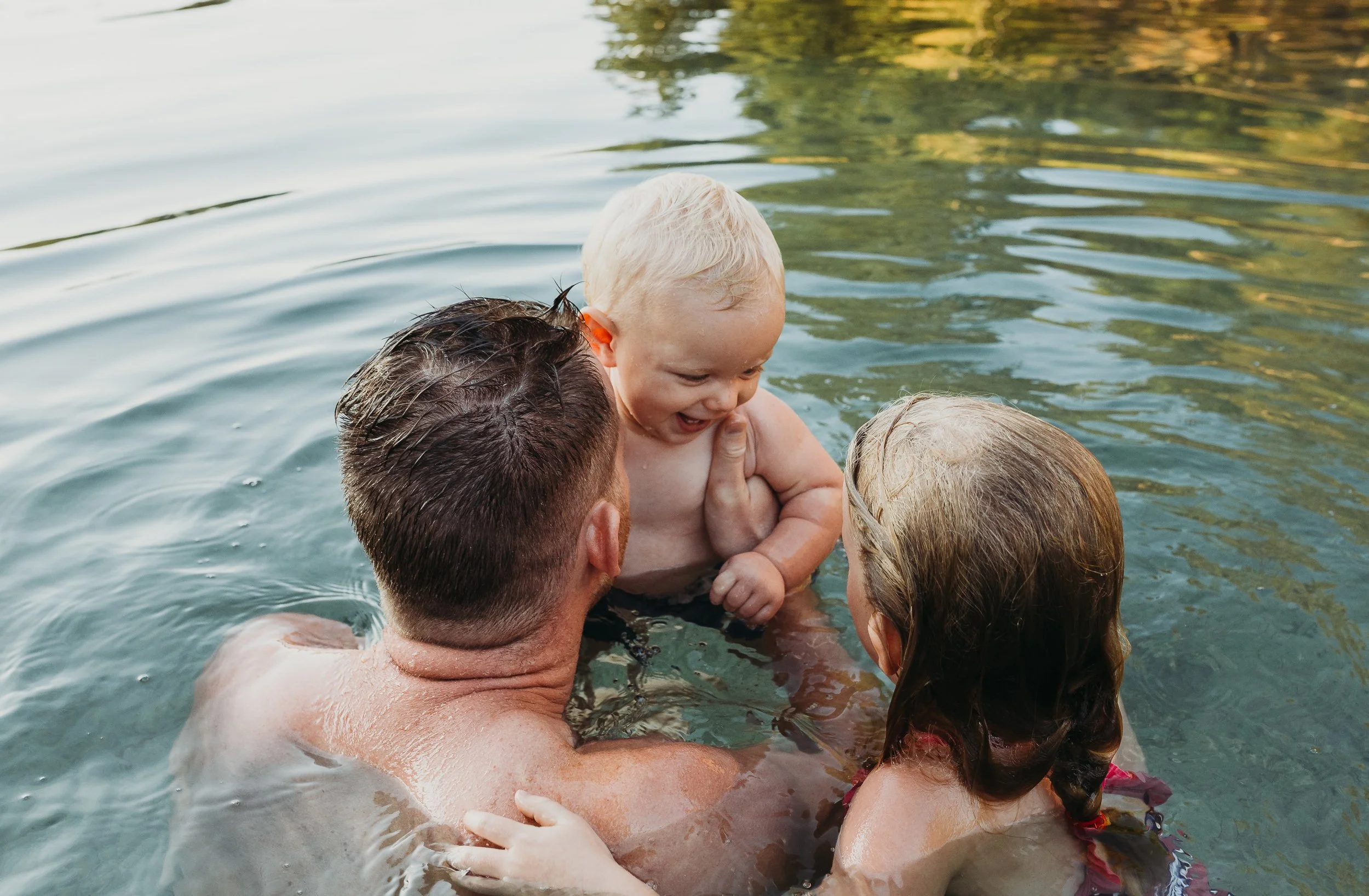 Family playing with baby in a lake.