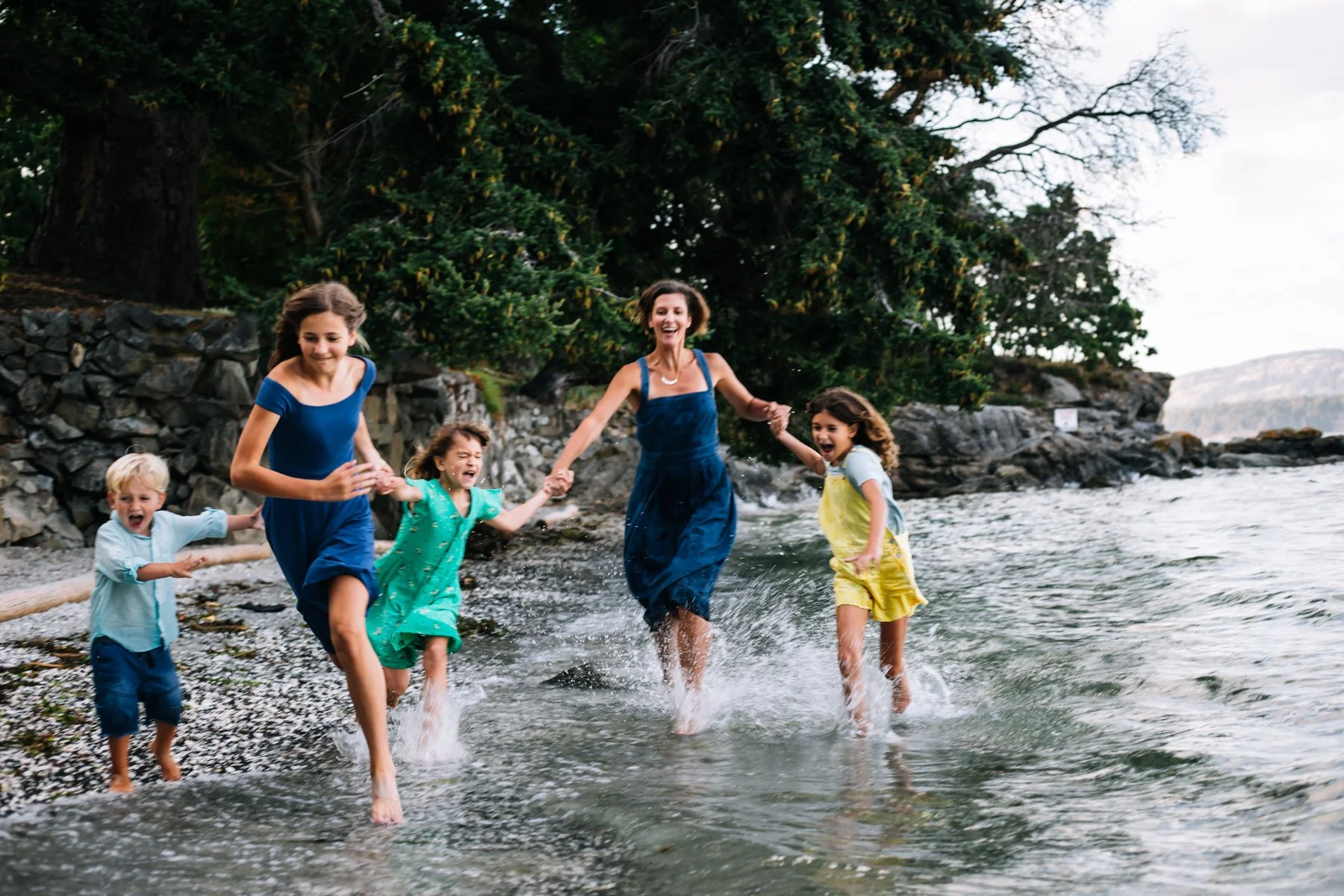 Family running on beach, splashing in water