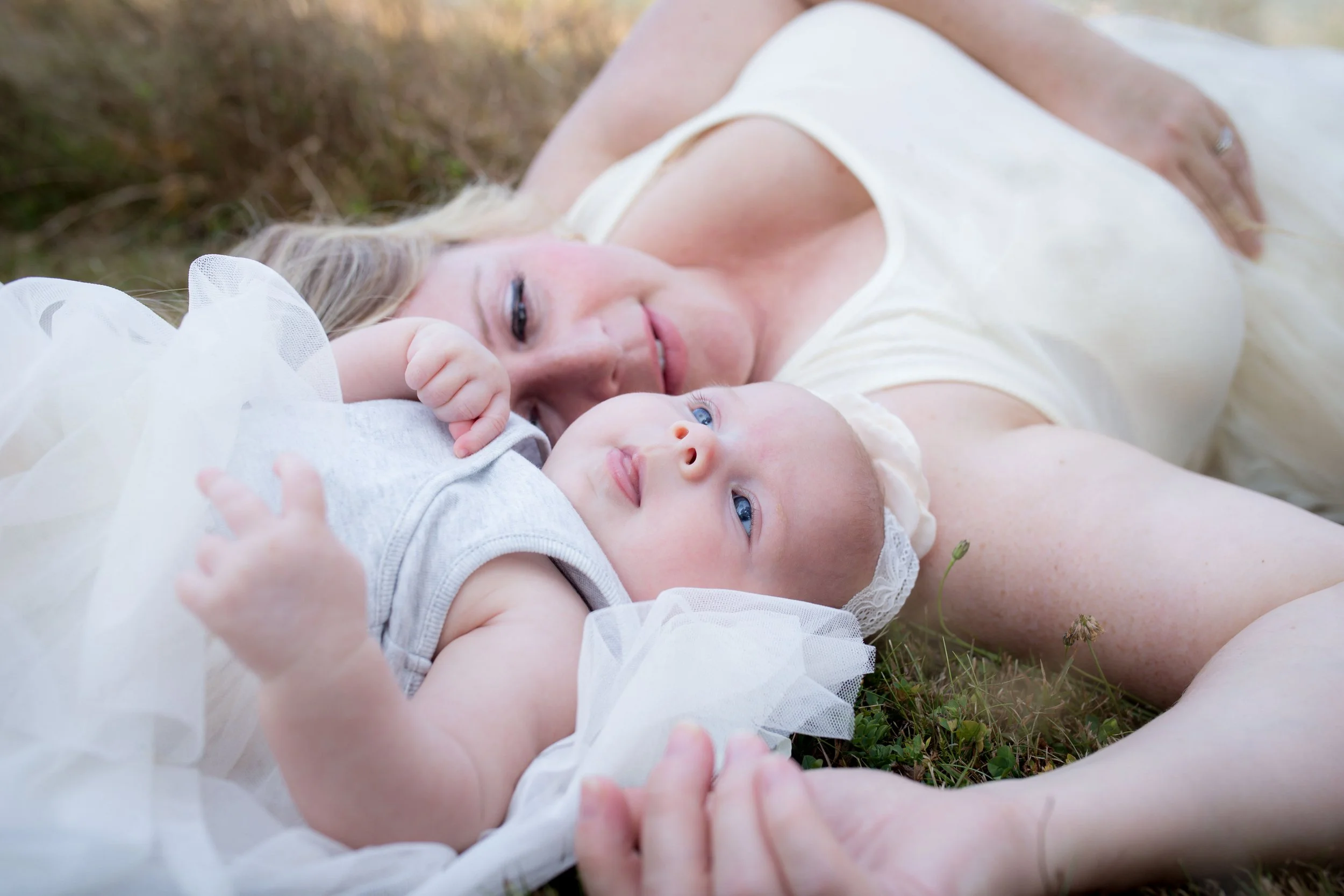 Mother and baby lying on grass, close-up shot.