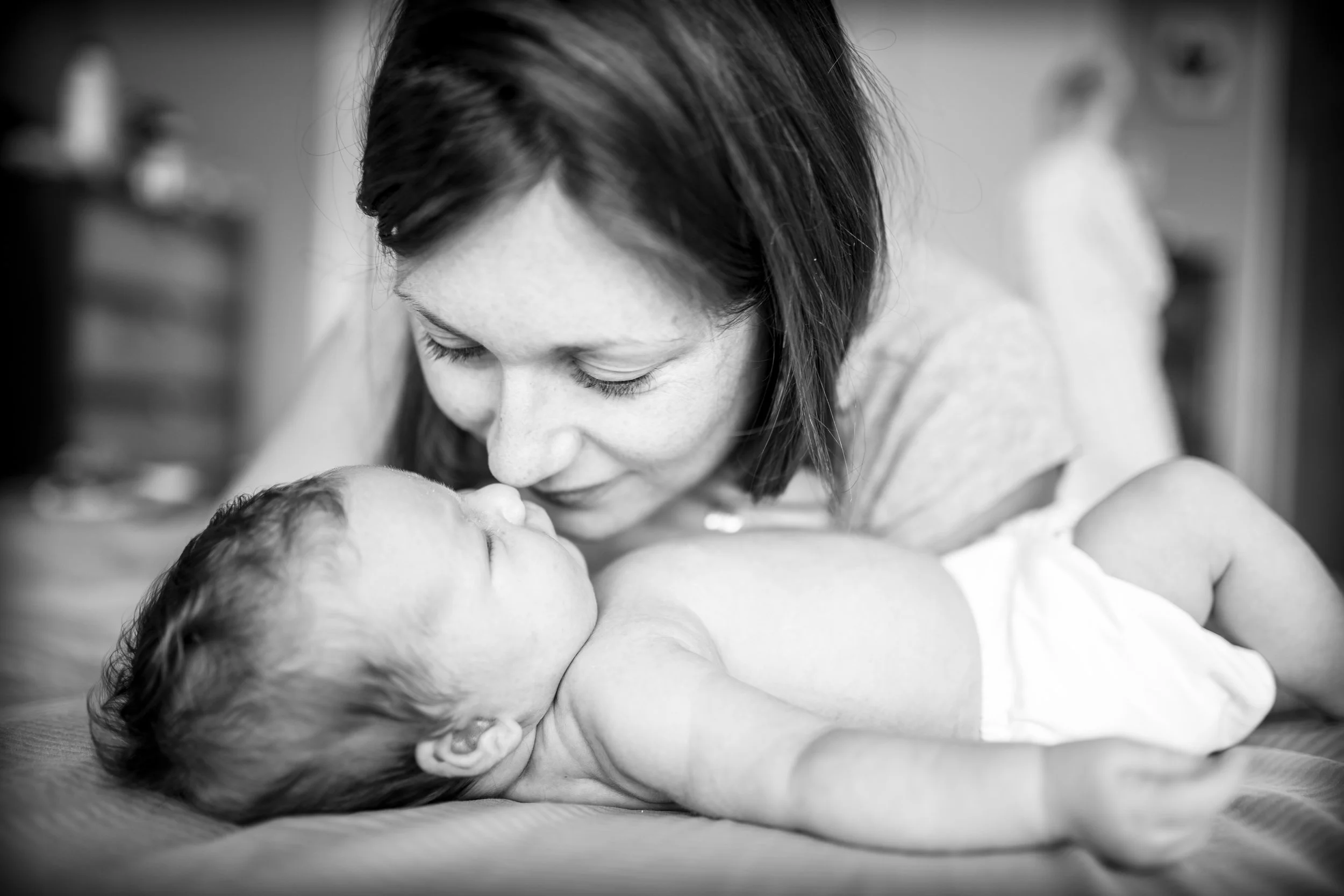 Mother lovingly kissing newborn baby on nose, black and white