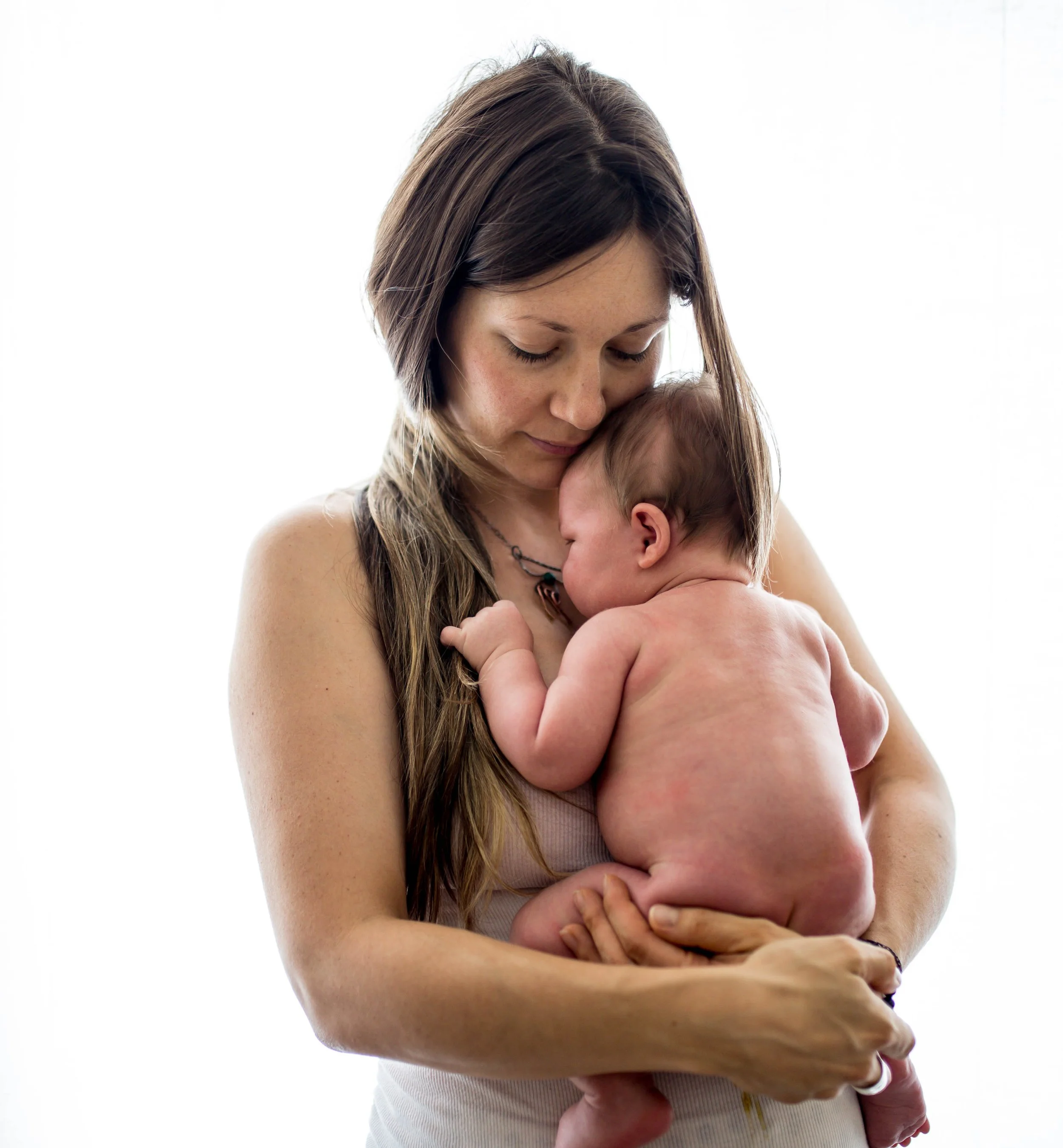 Mother holding newborn baby against white background.