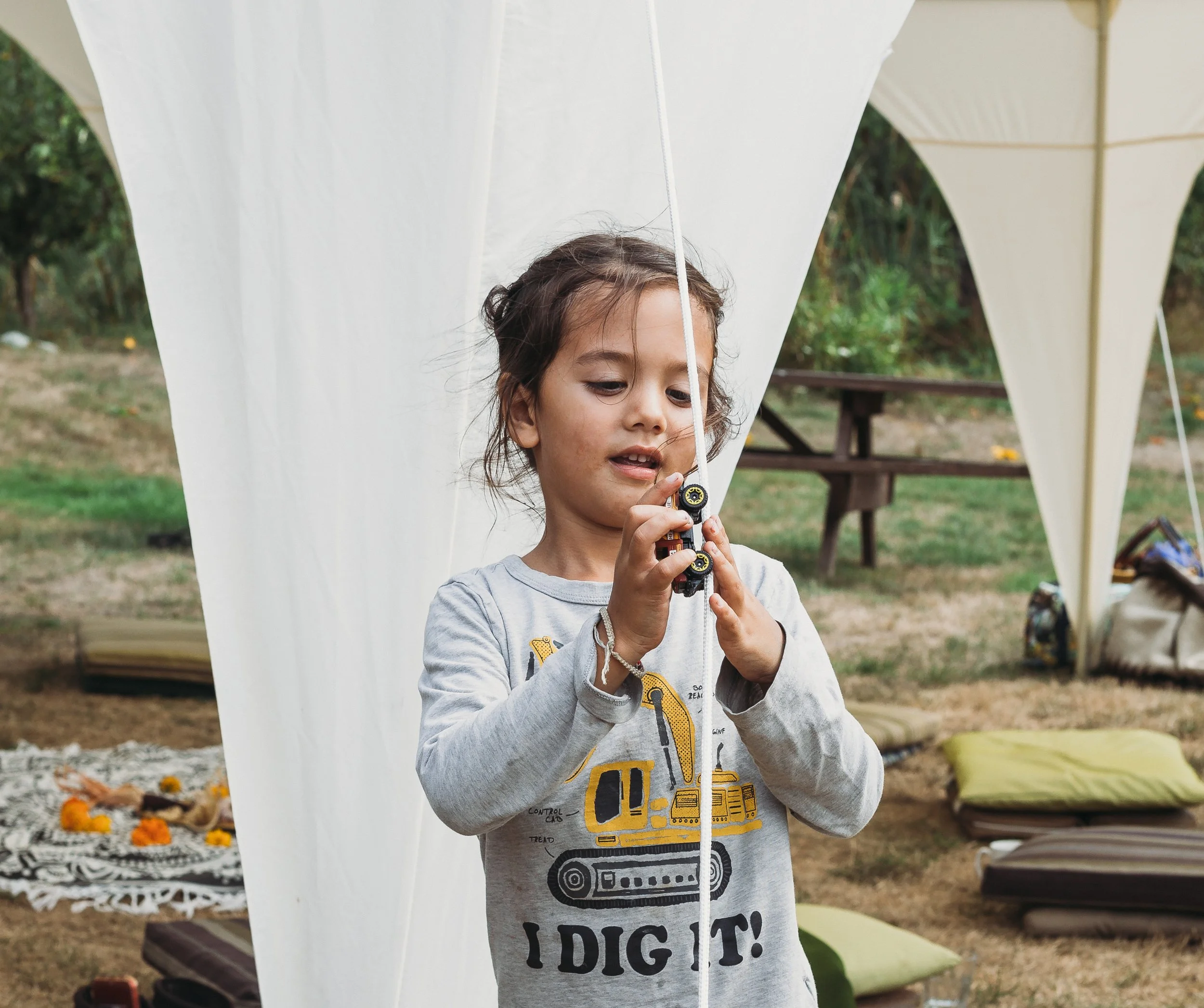 Child playing under a white tent outdoors