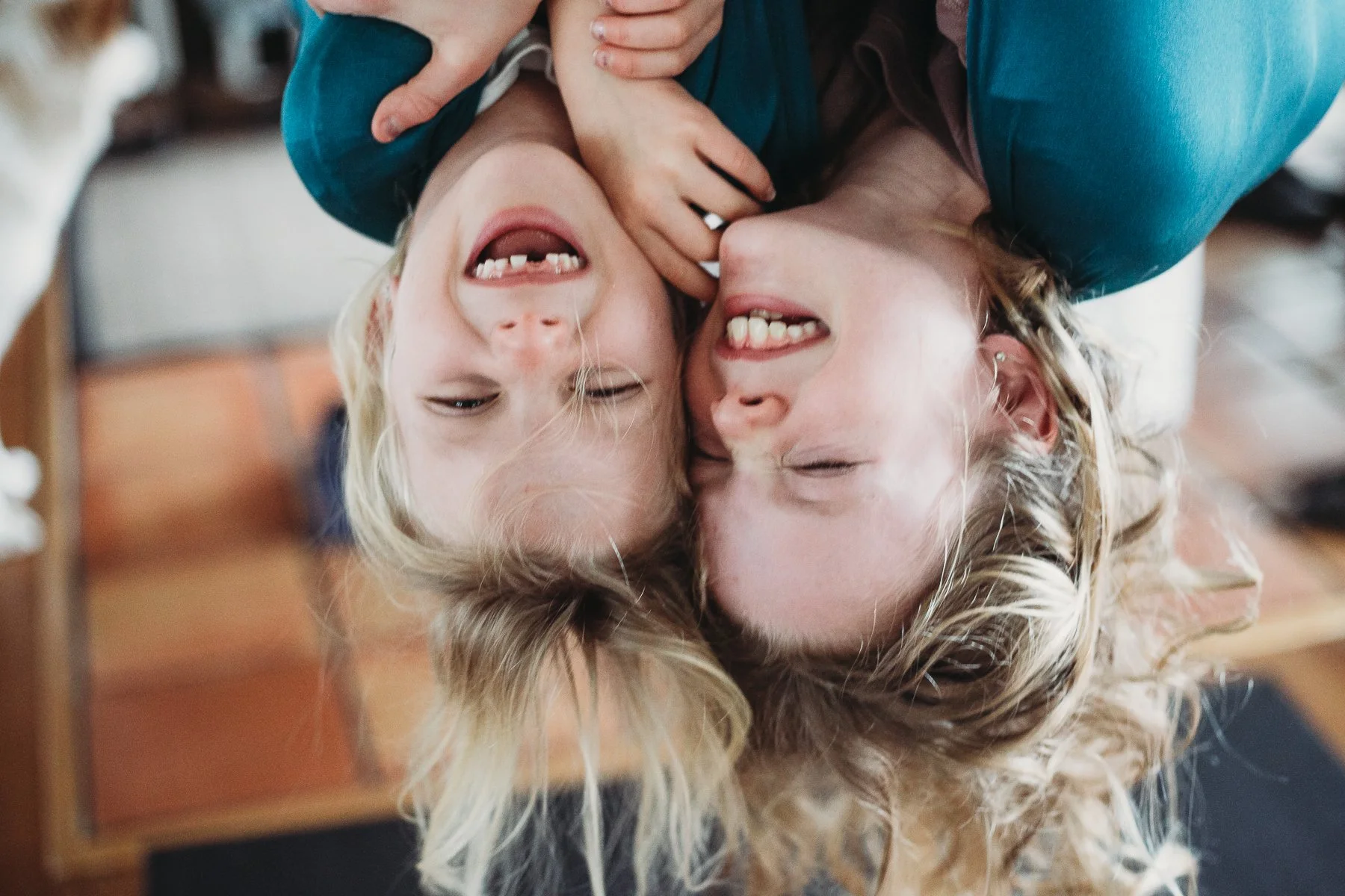 Two children laughing playfully while hanging upside down.