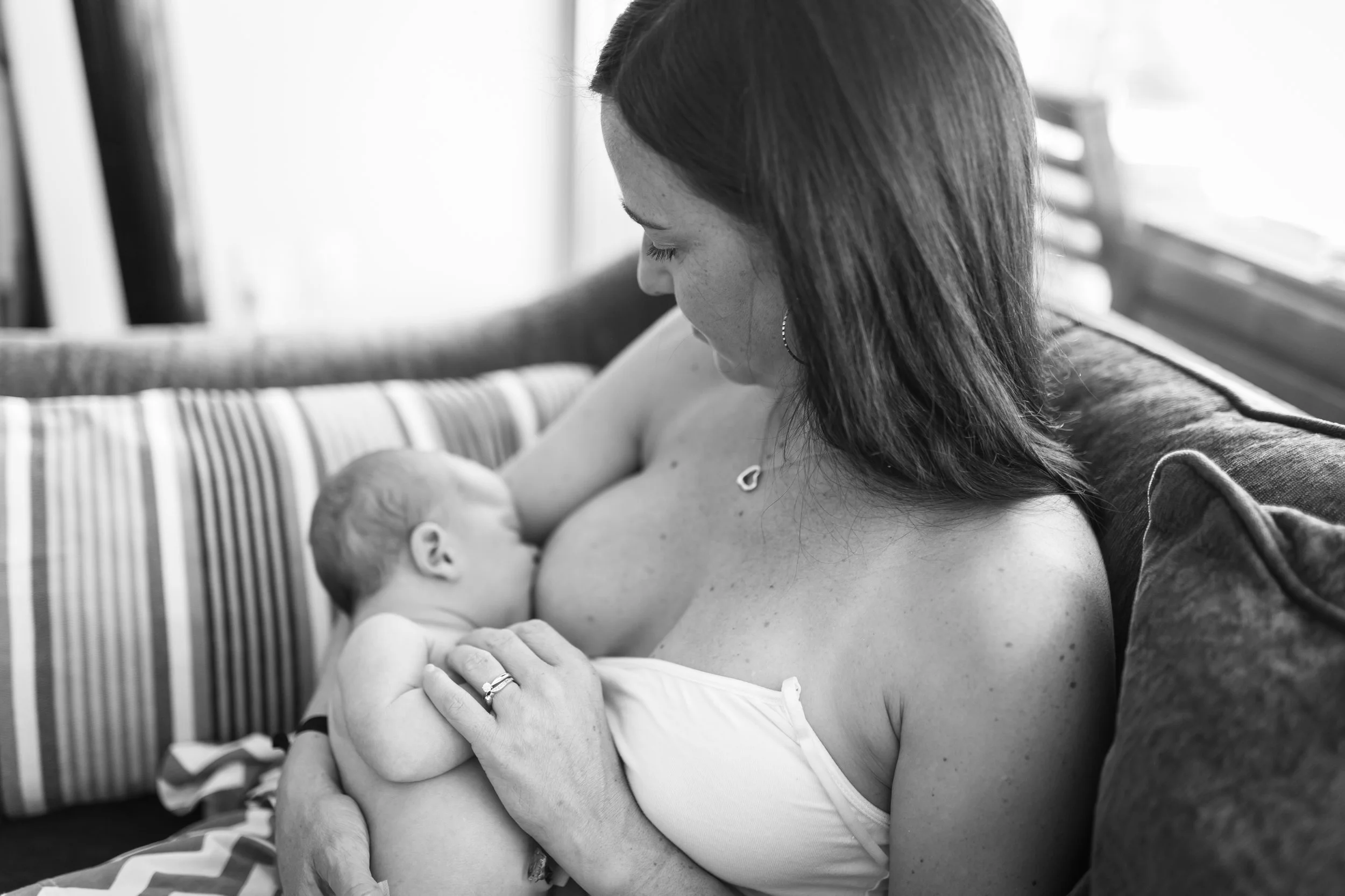 Mother breastfeeding baby on a couch in black and white.