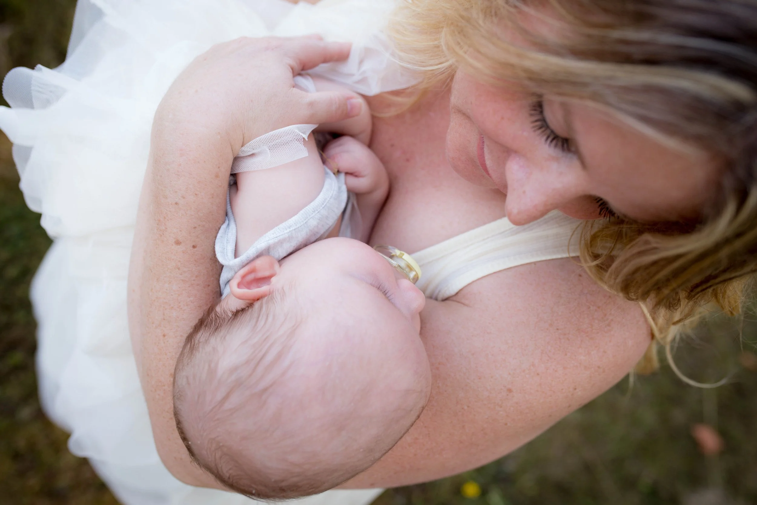 Close-up of a woman holding a sleeping baby with a pacifier.
