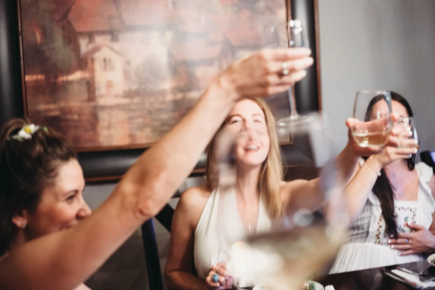 Group of women toasting with wine glasses at a table.