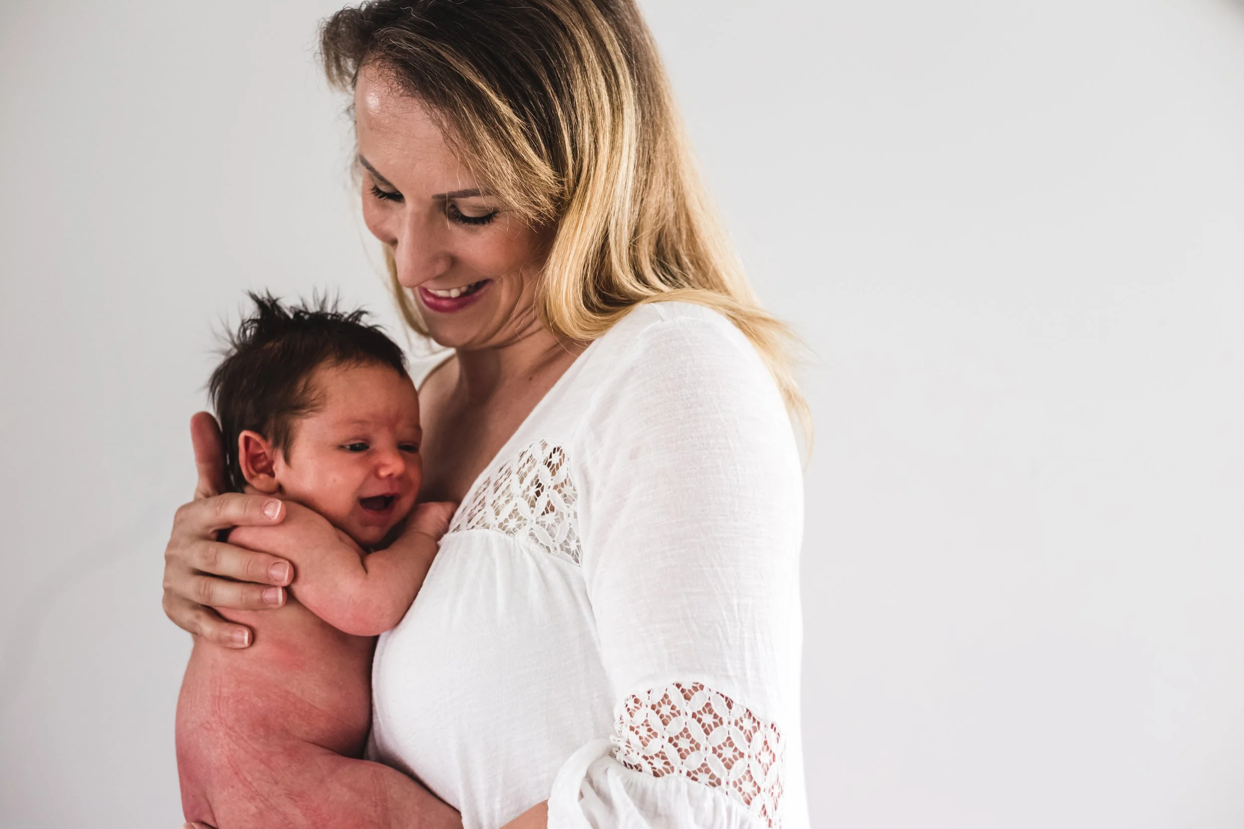 Mother holding newborn baby, both smiling