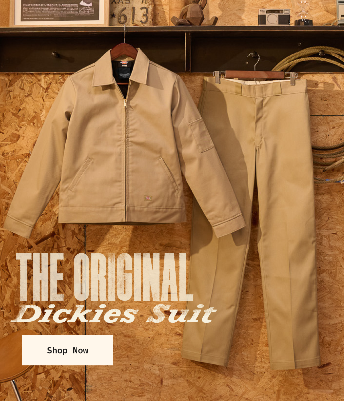 Dickies Eisenhower Jacket hung next to Dickies 874 pants in front of OSB wood, shelf of various props above