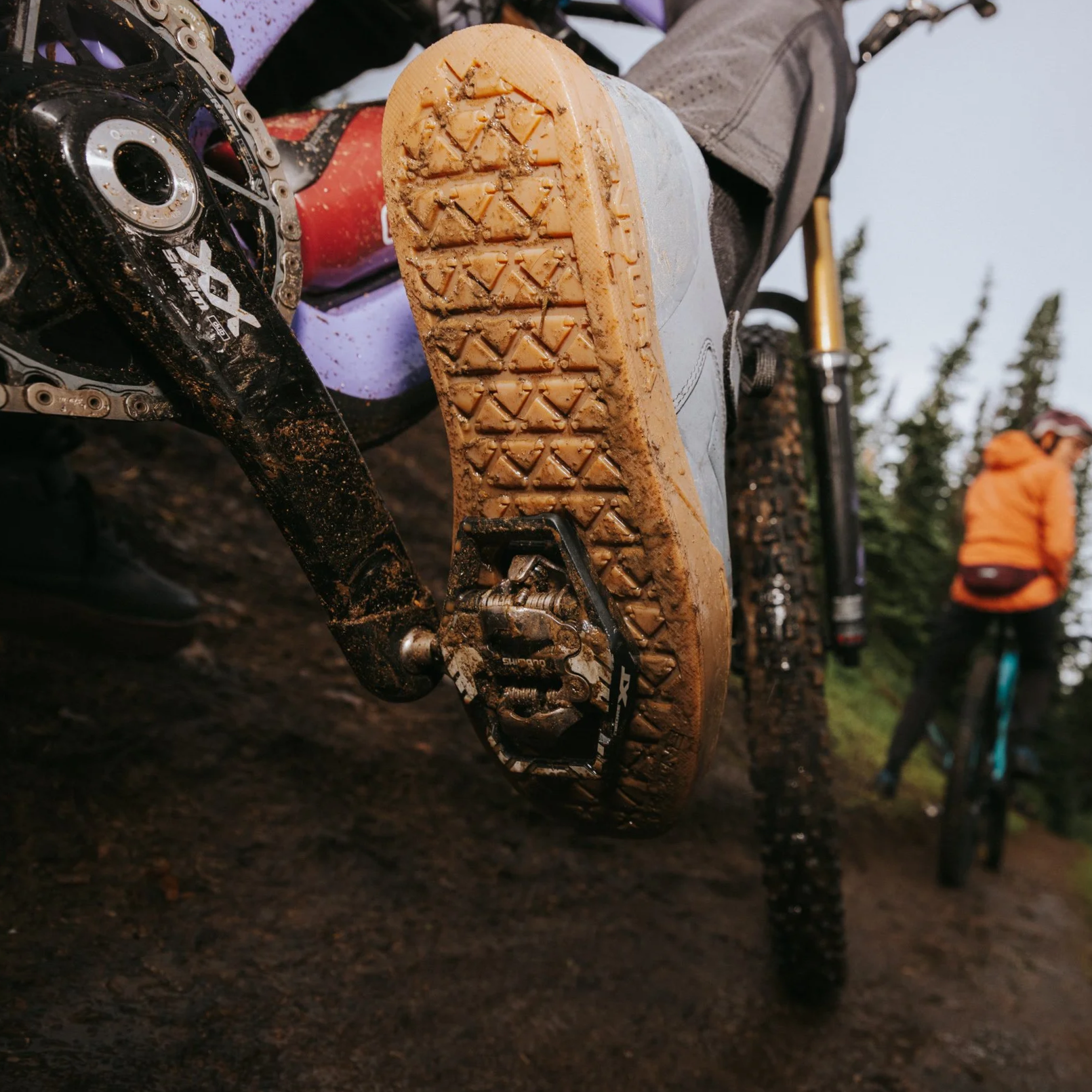 Close up action shot of the bottom of a muddy Endura mountain bike shoe clipped to Shimano XT trail pedal