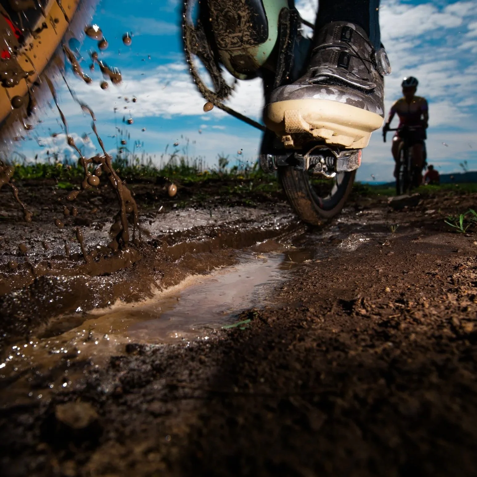 low angle photo of Shimano gravel bike shoe on pedal going through the mud