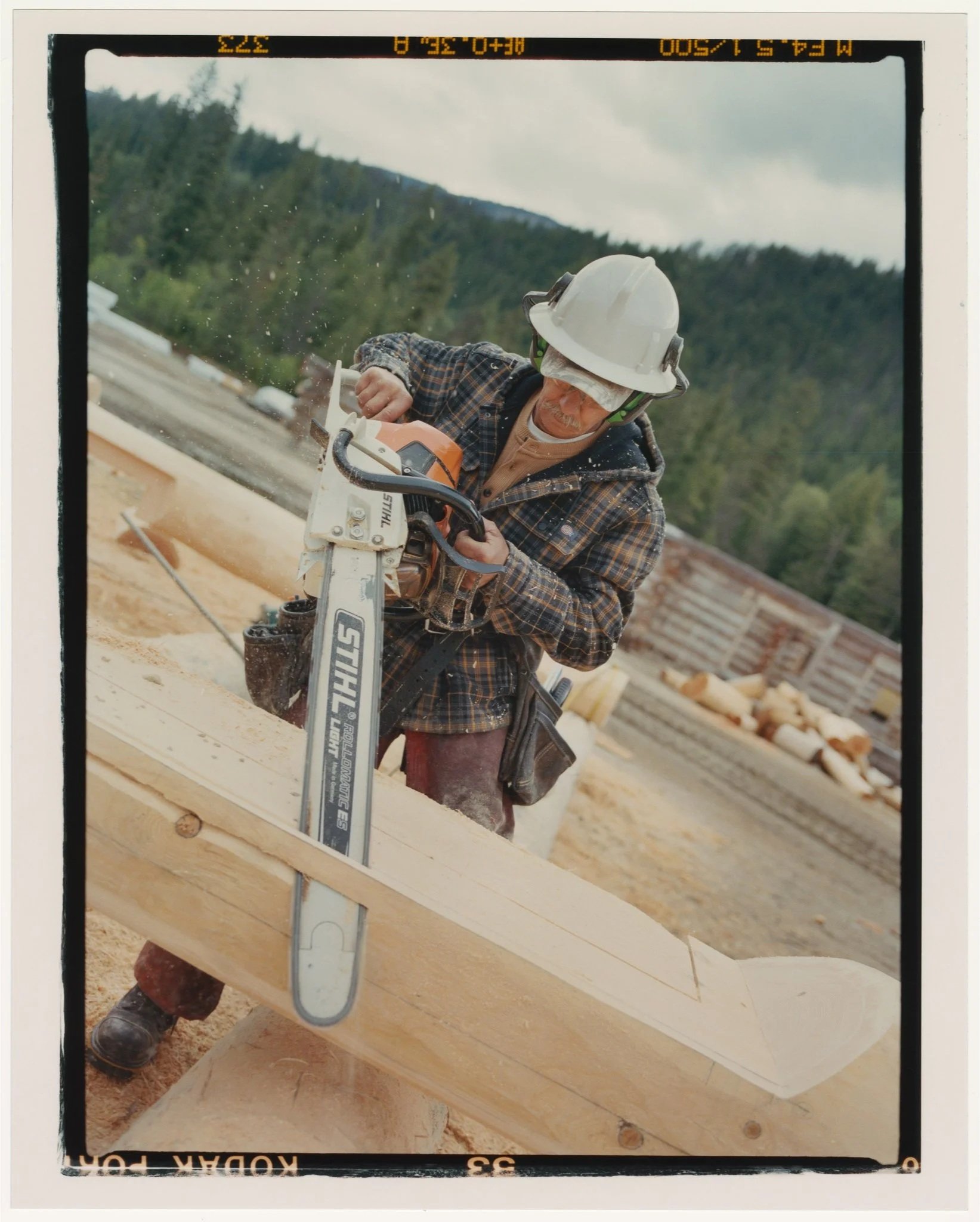 Man in Dickies Flannel Shirt Jacket carving log with large chain saw