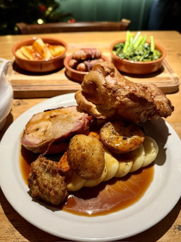 A plate wth a roast turkey dinner, yorkshire pudding, potatoes and vegetables on a wooden pub table