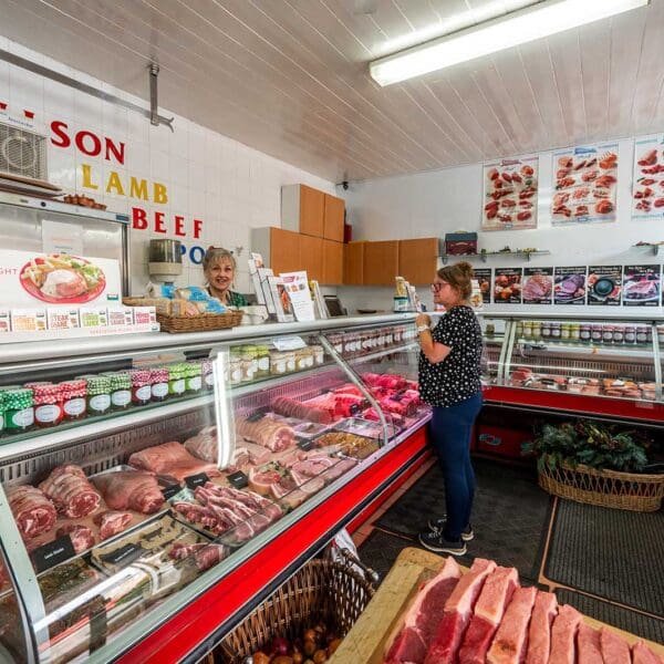 A man with a bike standing at a crosswalk in front of a tall, yellow residential building.