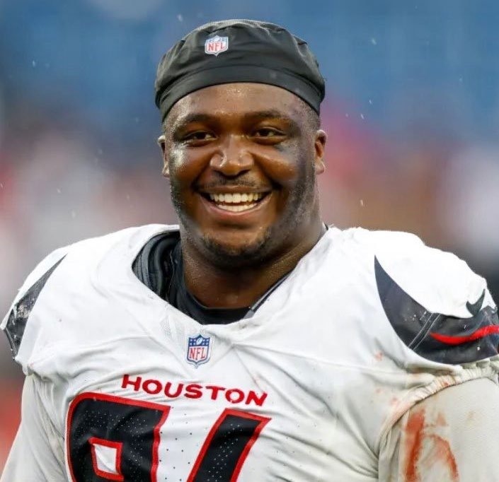 Close-up of a smiling American football player in a Houston Texans uniform and black NFL cap.