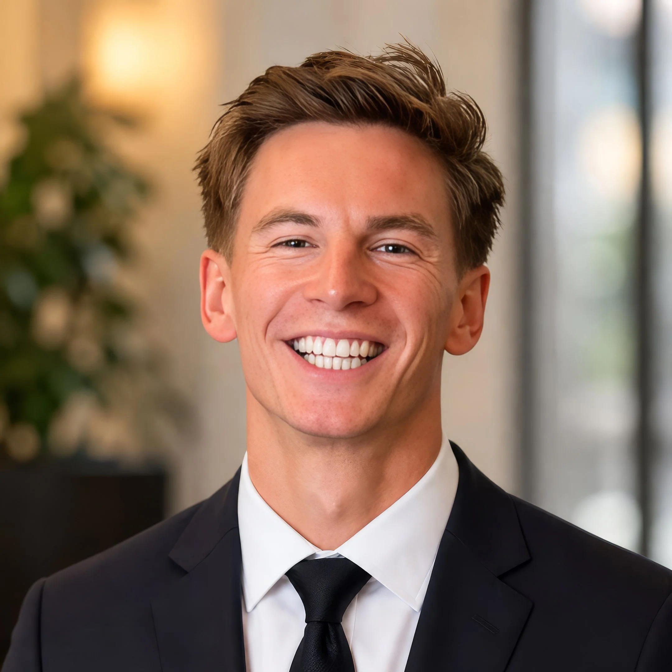 Dr BRadley Powell headshot. Smiling professional wearing a smart suit