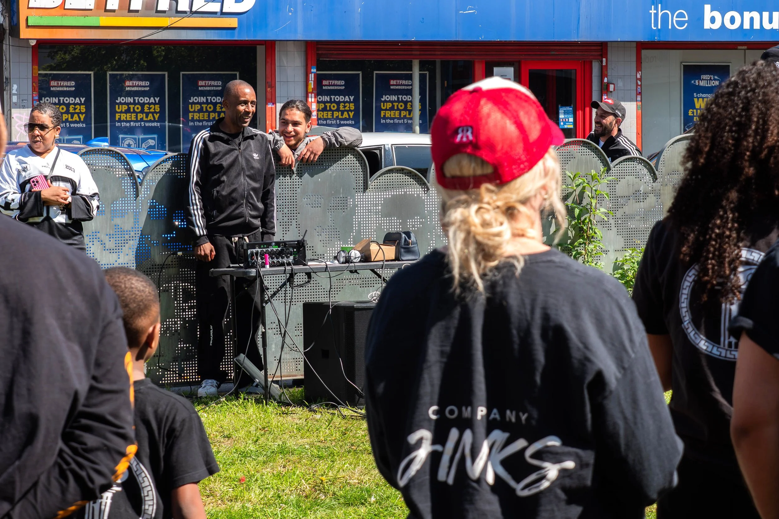 A person stood with a DJ set-up, with people in the foreground watching.