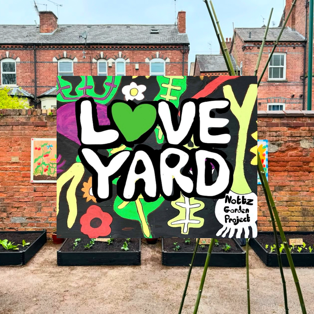 A mural with the words 'Love Yard' next to some vegetable beds.