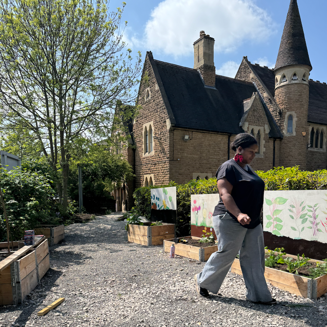 A person walking through a gravel garden with raised beds.