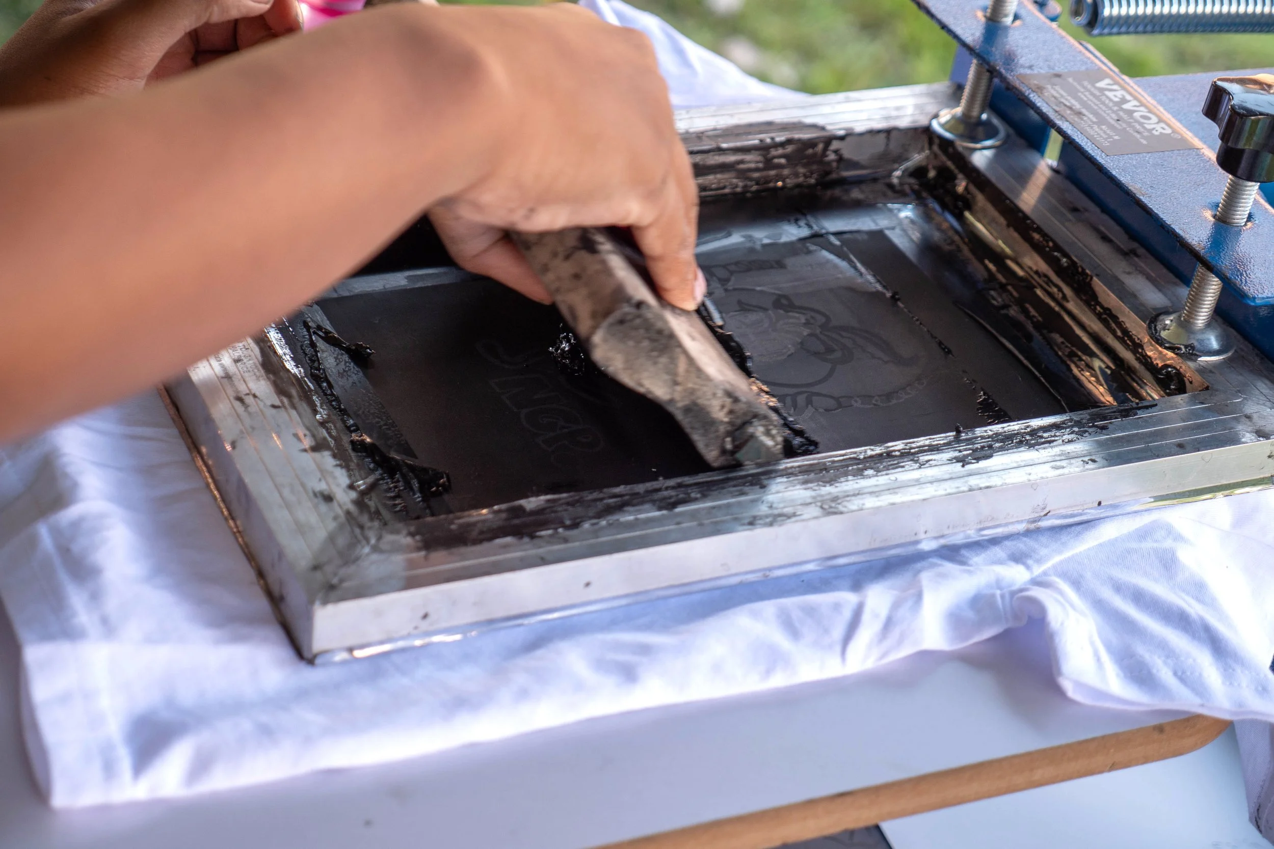 Close up of hands screen-printing a t-shirt.