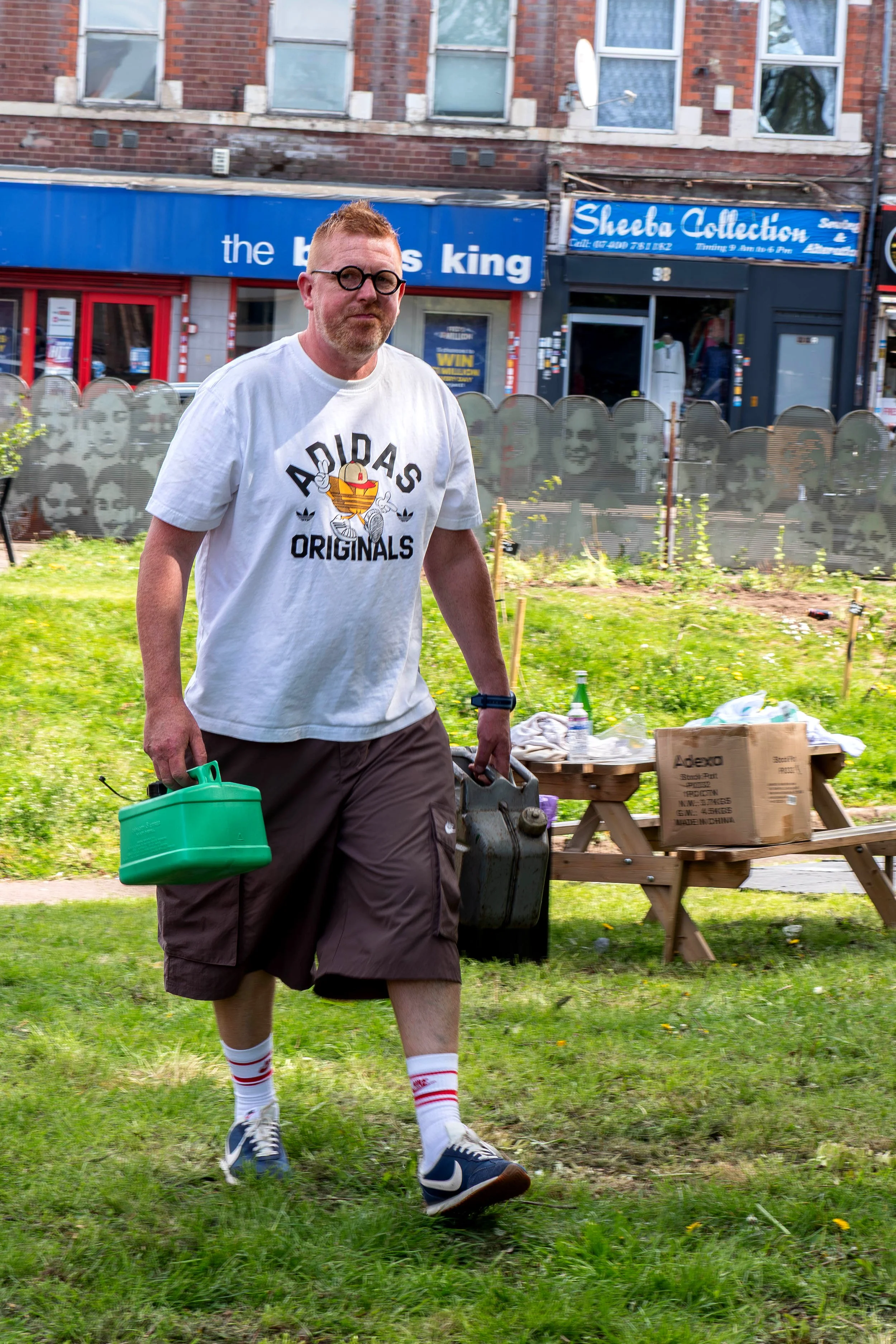 A person carrying two watering cans looking intrepid. 
