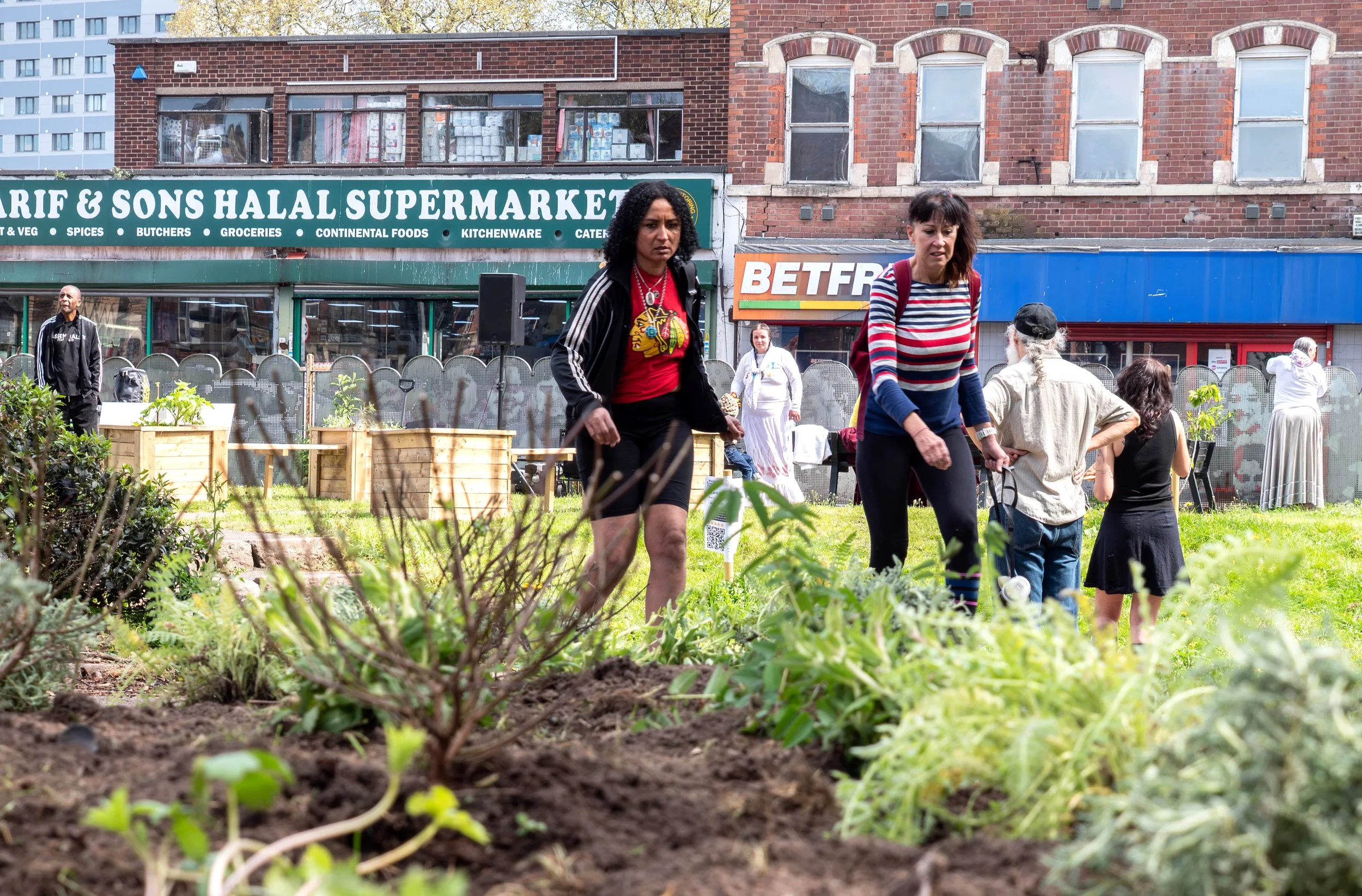 A low shot of two people walking past a freshly planted bed. 