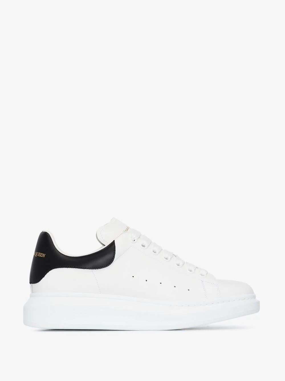 White sneaker with a black accent at the heel, gold lettering on the black part, and white laces.