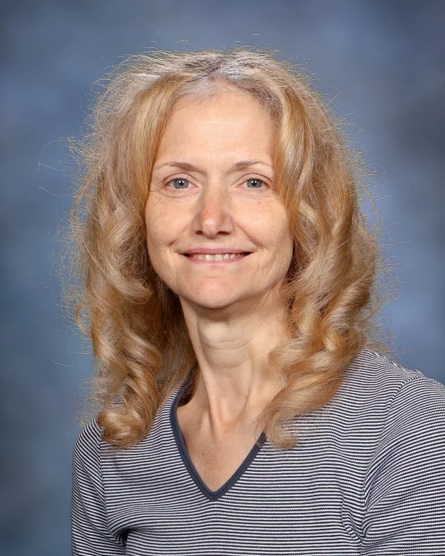 Portrait of Barbara Mattuzzi, Floating Assistant at Webster Montessori School, smiling against a blue background.