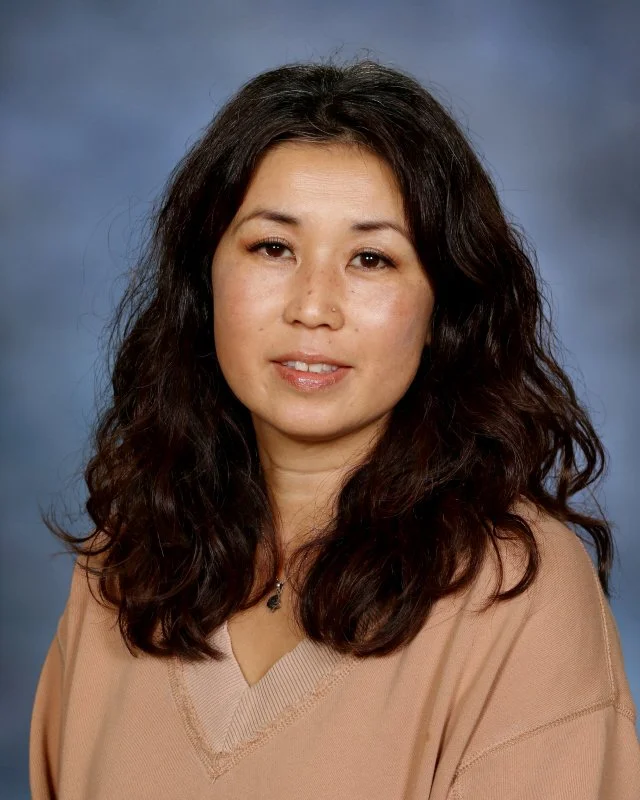 Portrait of Yasuko Poutre, Toddler Directress at Webster Montessori School, smiling against a blue background.