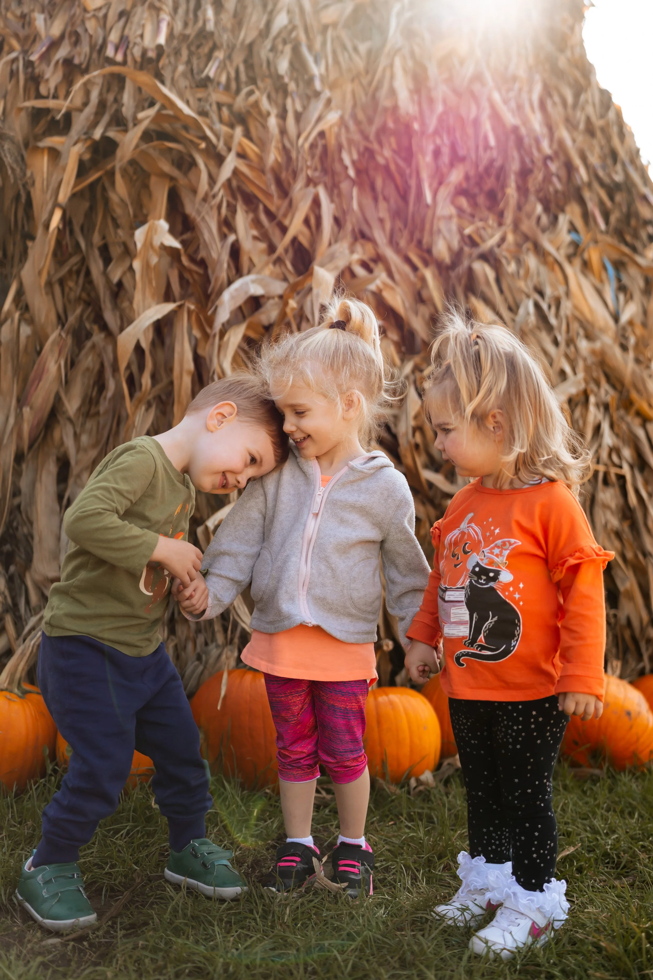 Three toddler students holding hands in a pumpkin patch.