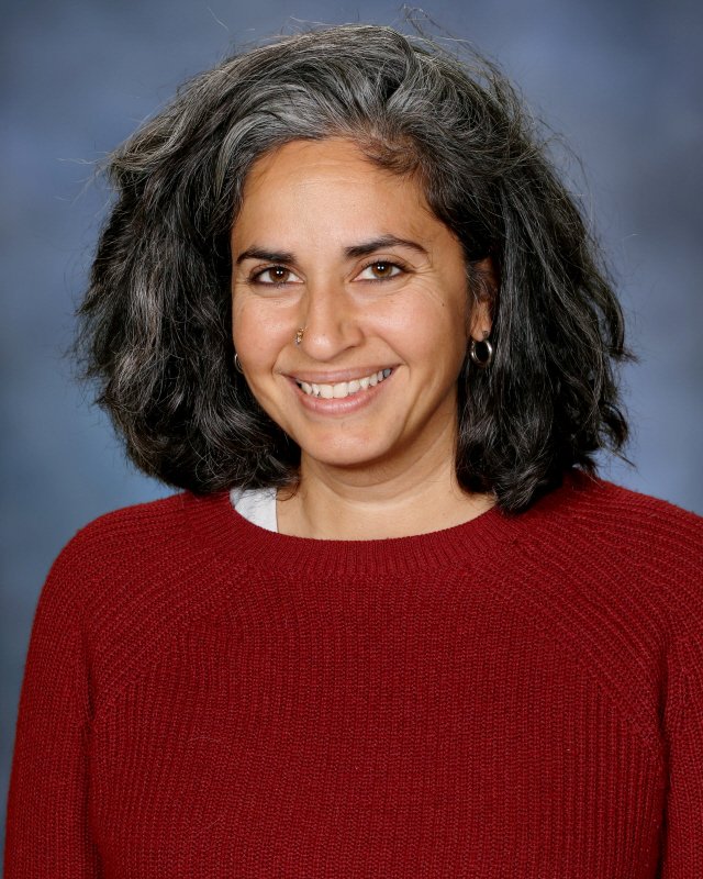Portrait of Netra Srikanth, Head of School at Webster Montessori School, smiling against a blue background.