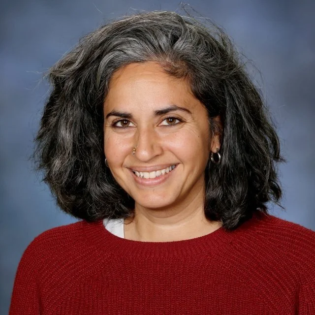 Portrait of Netra Srikanth, Head of School , smiling against a blue background.