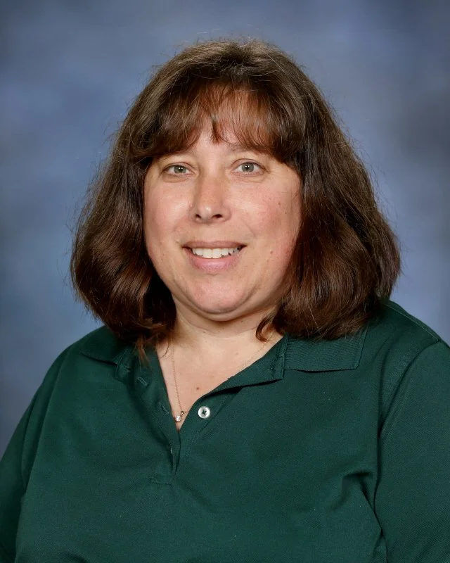 Portrait of Alysa Slavinksky, Wrap-Around Caregiver at Webster Montessori School, smiling against a blue background.