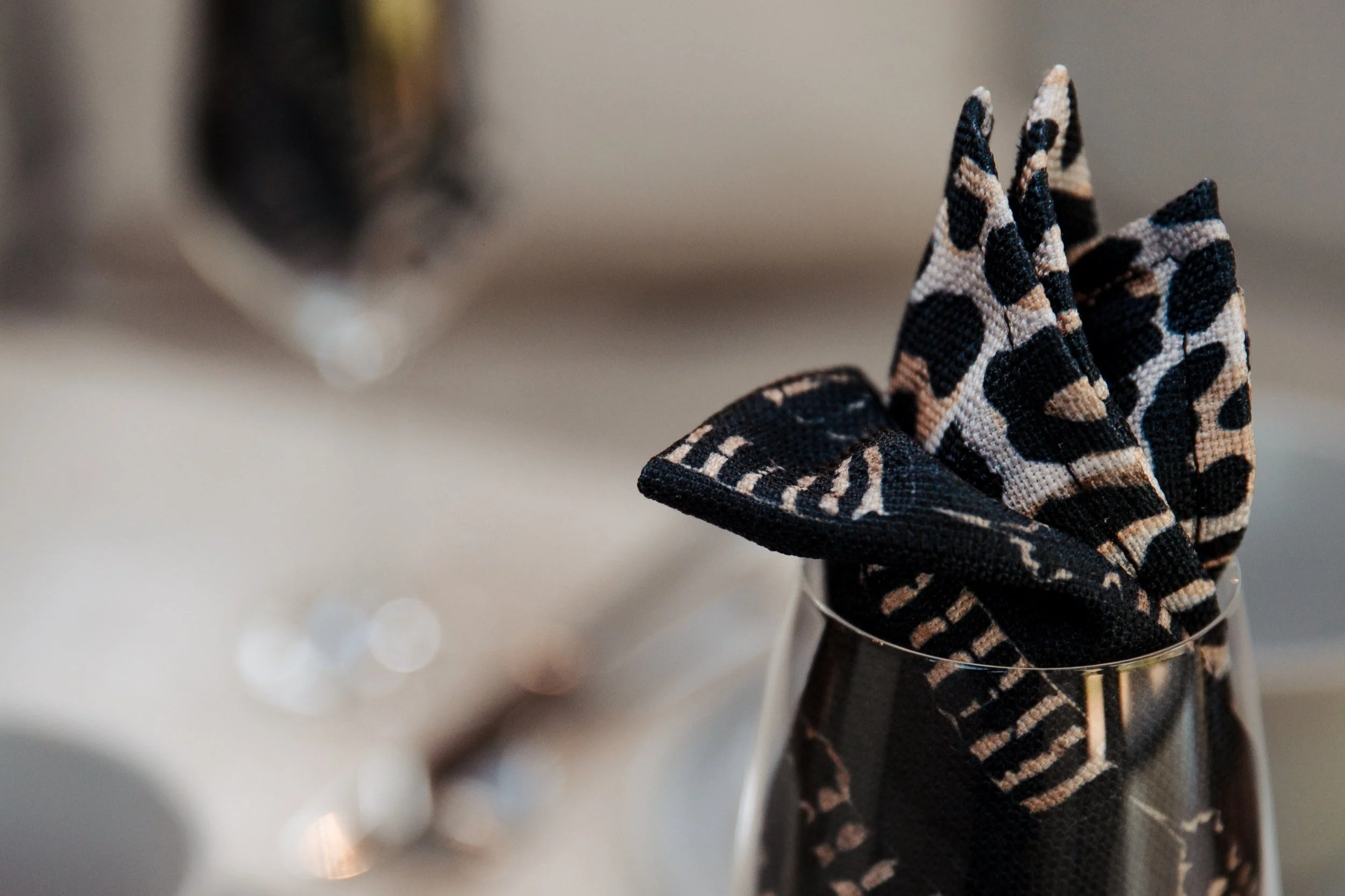 A glass with leopard print cloth napkin folded inside