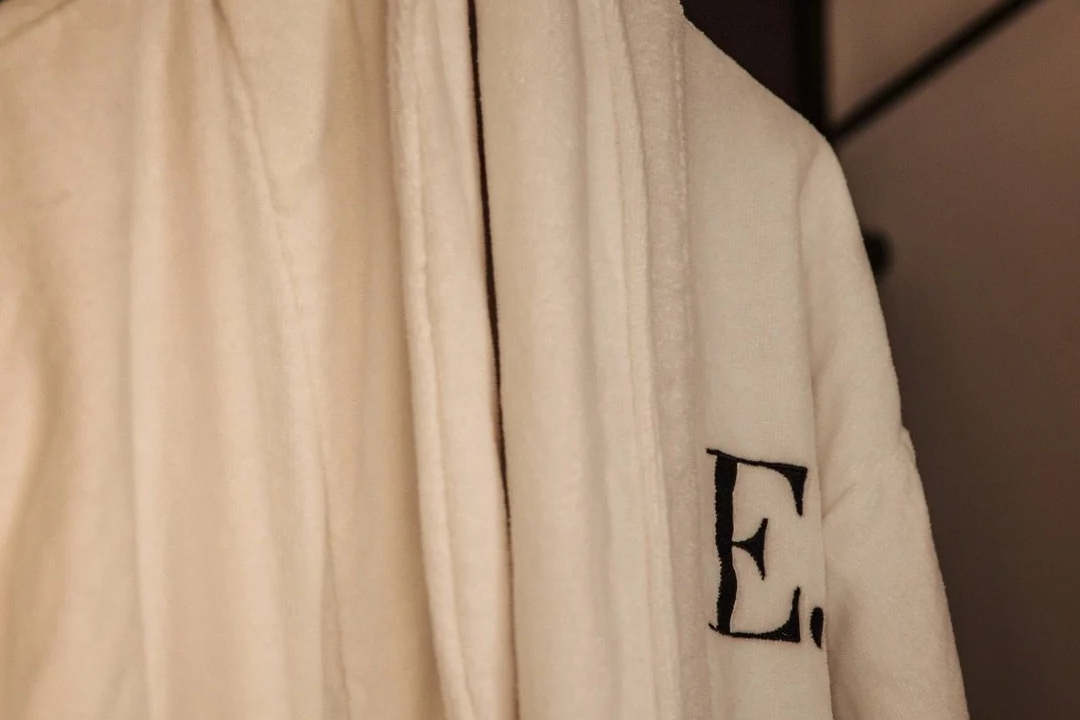 Close-up of a beige jacket with a black letter 'E' on the sleeve.