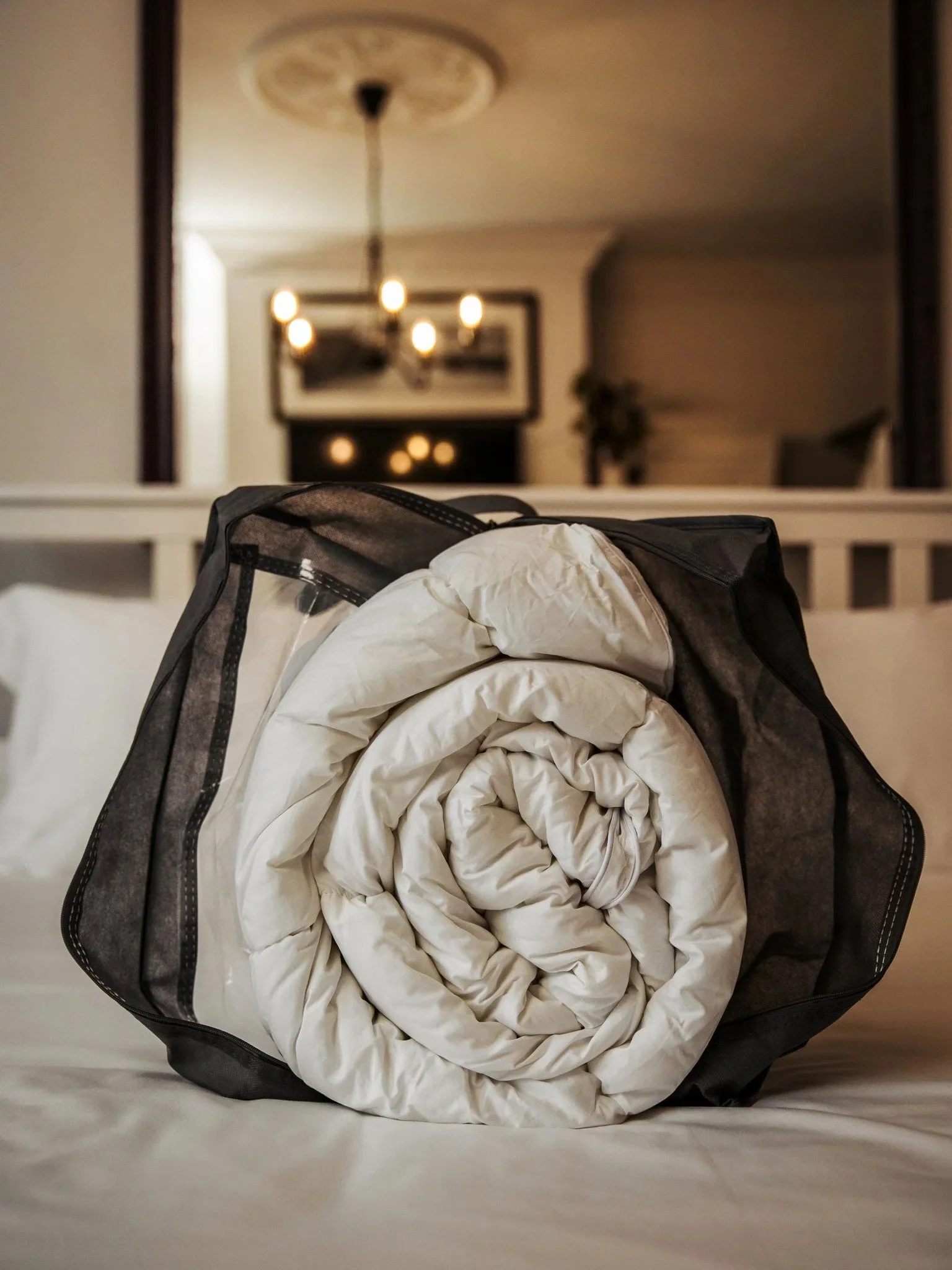 Rolled-up white comforter inside a black mesh laundry bag on a bed.