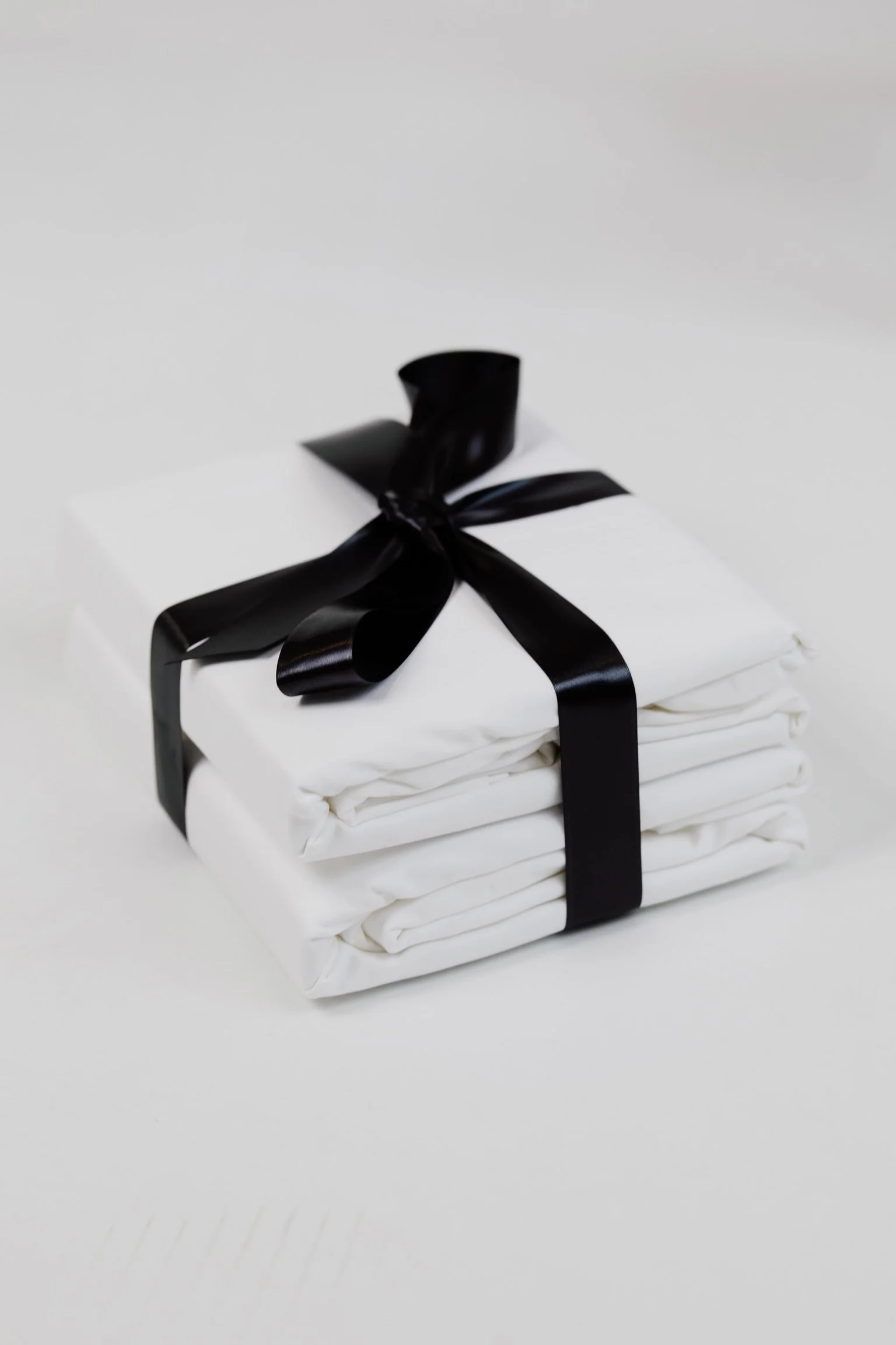 Stack of white folded clothes tied with a black ribbon.