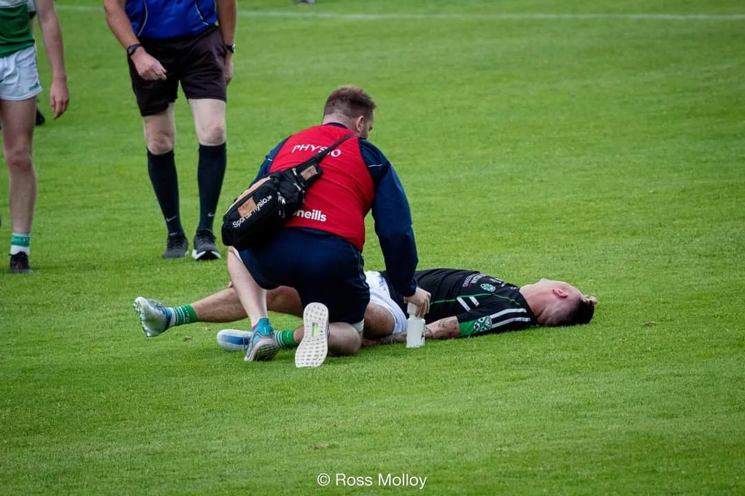 A sports medic treats an injured football player lying on the field during a game.