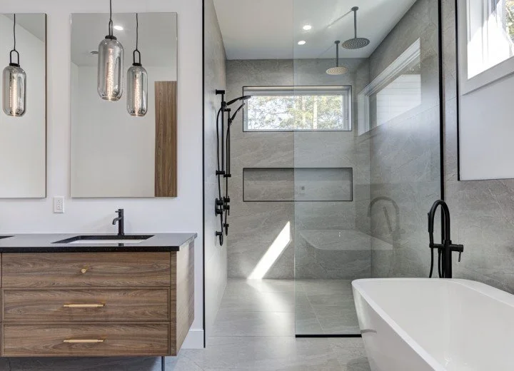 Salle de bain moderne avec un meuble-lavabo en bois, deux miroirs rectangulaires, une douche vitrée à l'italienne avec deux pommes de douche pluie, et une baignoire blanche.