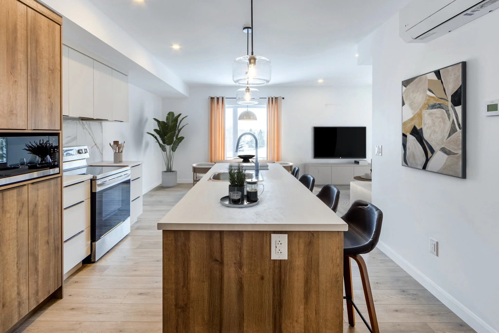 Cuisine moderne avec îlot central, tabourets en cuir, four encastré, évier, plante verte, télévision murale, et décor minimaliste avec tableau abstrait.