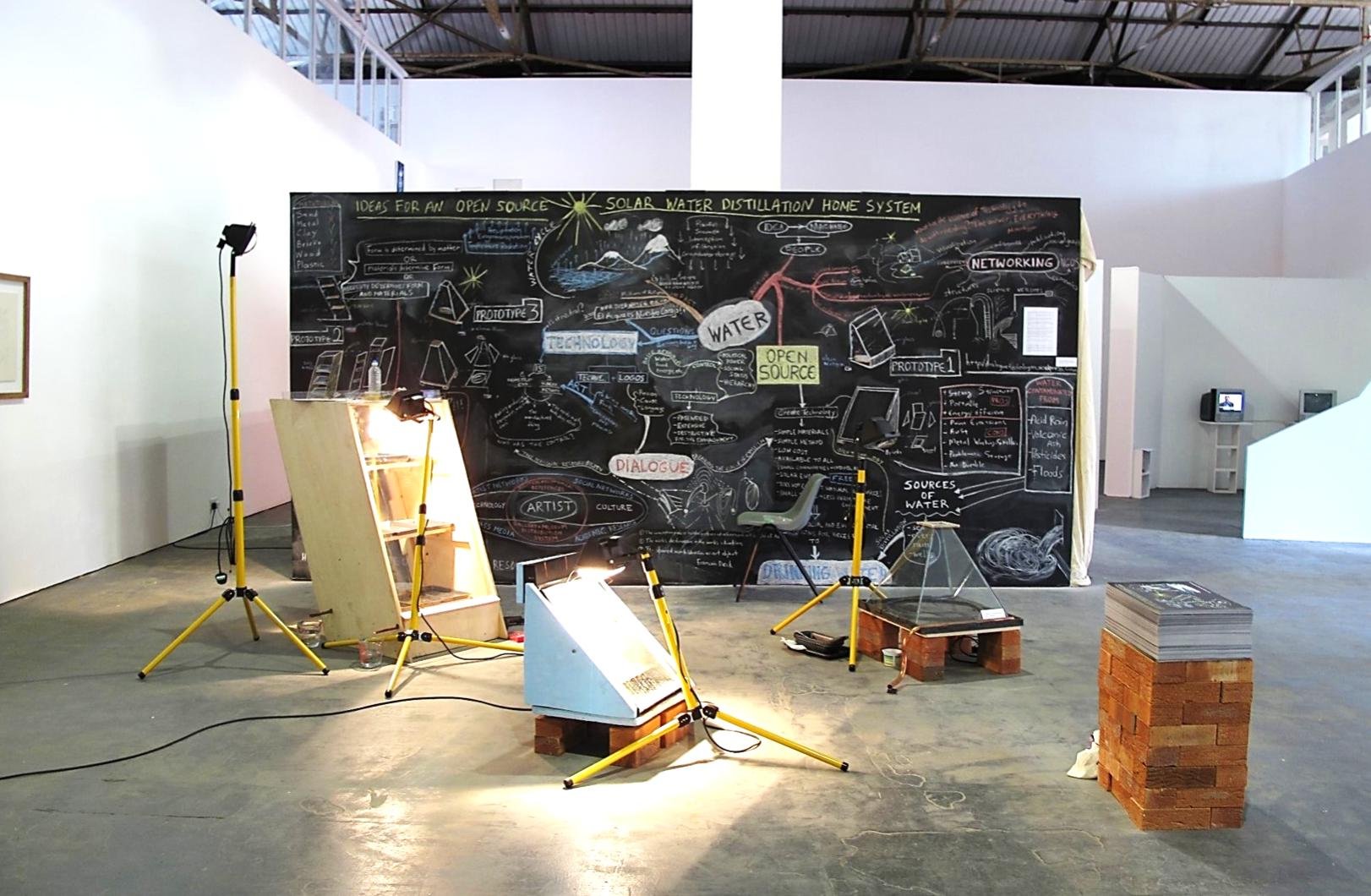 large scale gallery installation with big blackboard_prototypes of desalination machines and bright lights