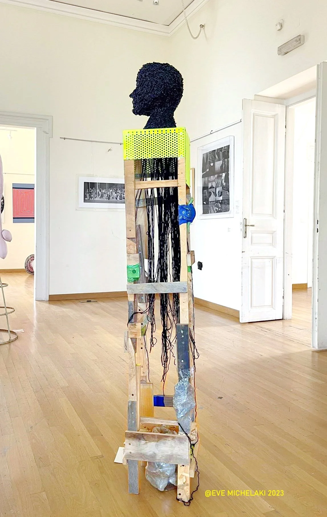 sculpture of  bust made from black material on a mixed materials pedestal_ depicting  Ariadne from Greek mythology_in gallery exhibition environment 