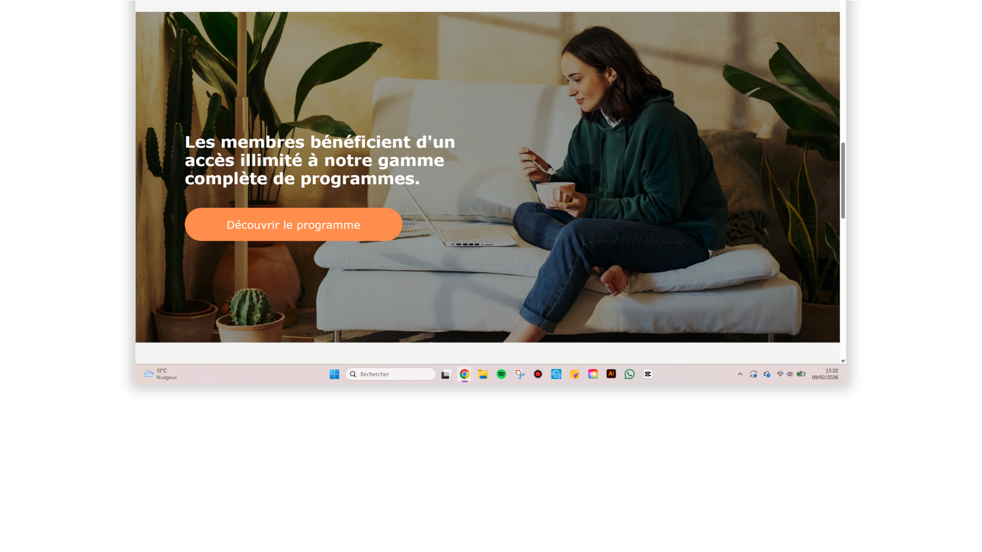 Une femme assise sur un canapé blanc, utilisant un ordinateur portable et mangeant une soupe, entourée de plantes vertes dans une pièce chaleureuse.