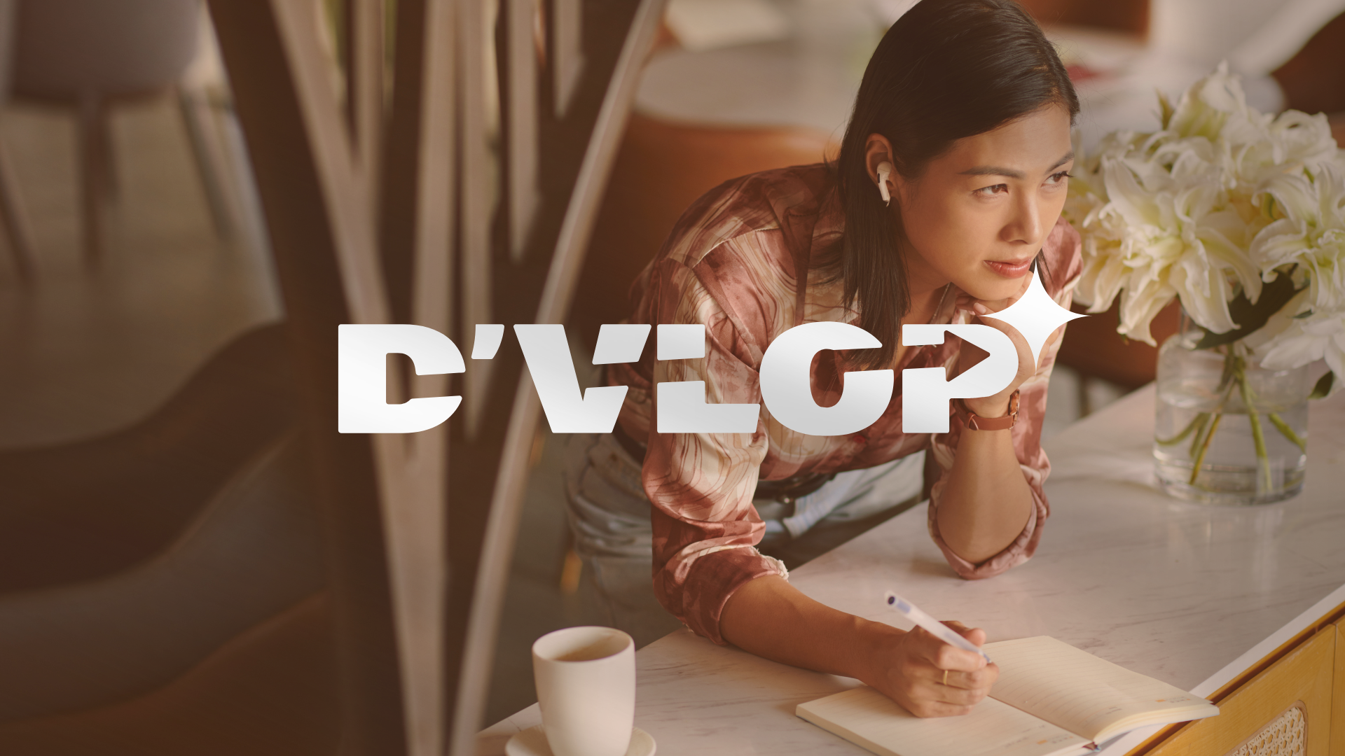 Une femme assise à une table, écrivant dans un carnet, avec un bouquet de fleurs blanches à côté d'elle.