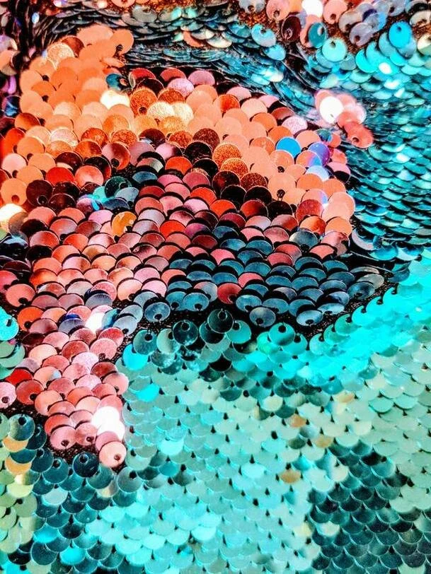 Close-up of multicolored sequins arranged in a swirling pattern.