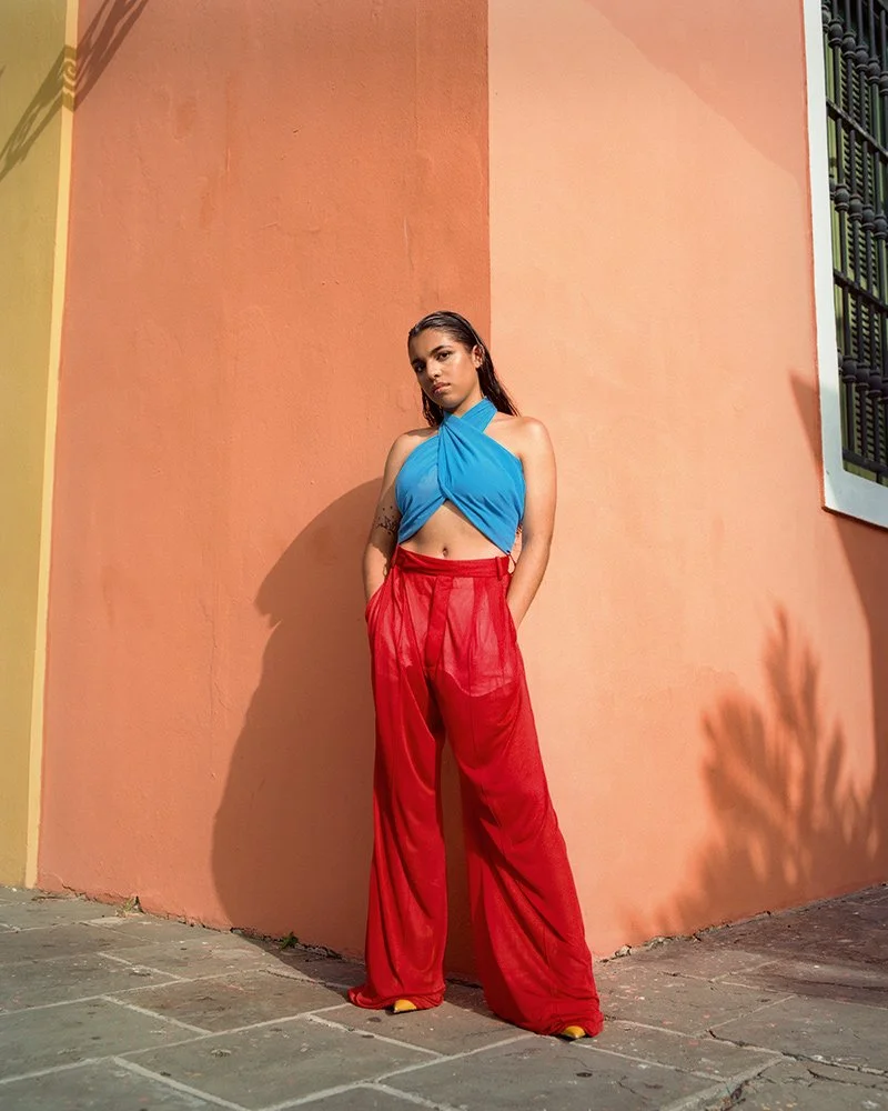 Isabel Valentín standing up against a painted wall in San Juan, PR